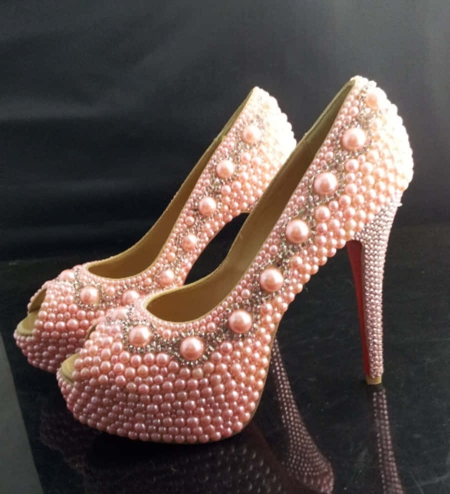 Pink Shoes 桌布 壁紙 — 優雅的粉紅色珍珠鑲嵌露趾高跟鞋，紅色鞋底，放置在光滑的黑色表面上，背景為深色。