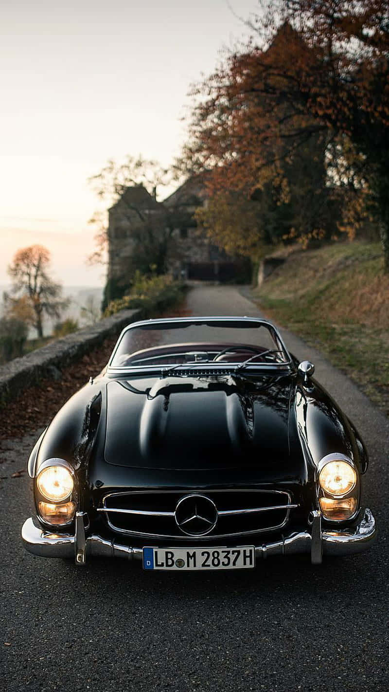 黑色 vintage Mercedes-Benz 開篷車在秋季道路上，夕陽下。