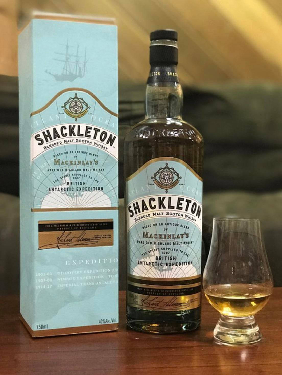 Shackleton威士忌瓶和盒，連同玻璃杯，在木桌上。
