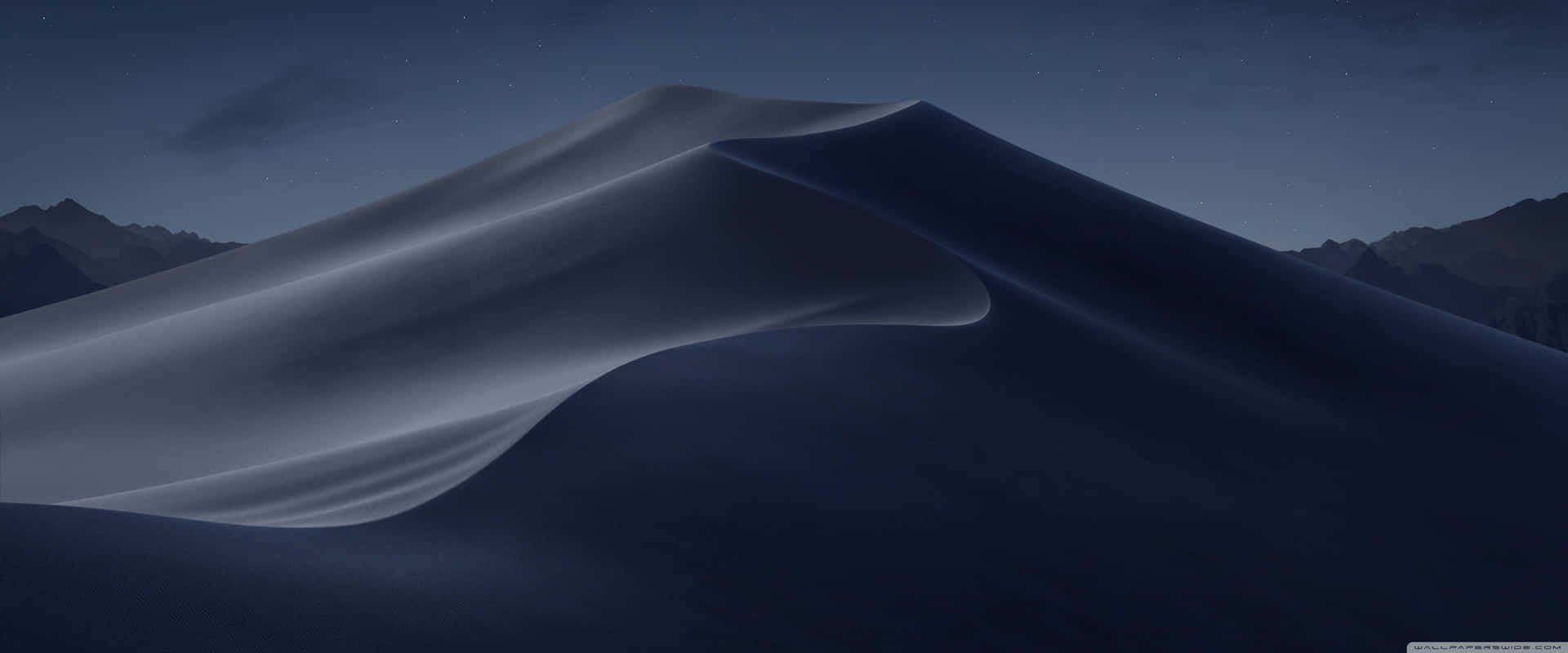 繁星夜空下平滑的沙漠沙丘與山巒剪影