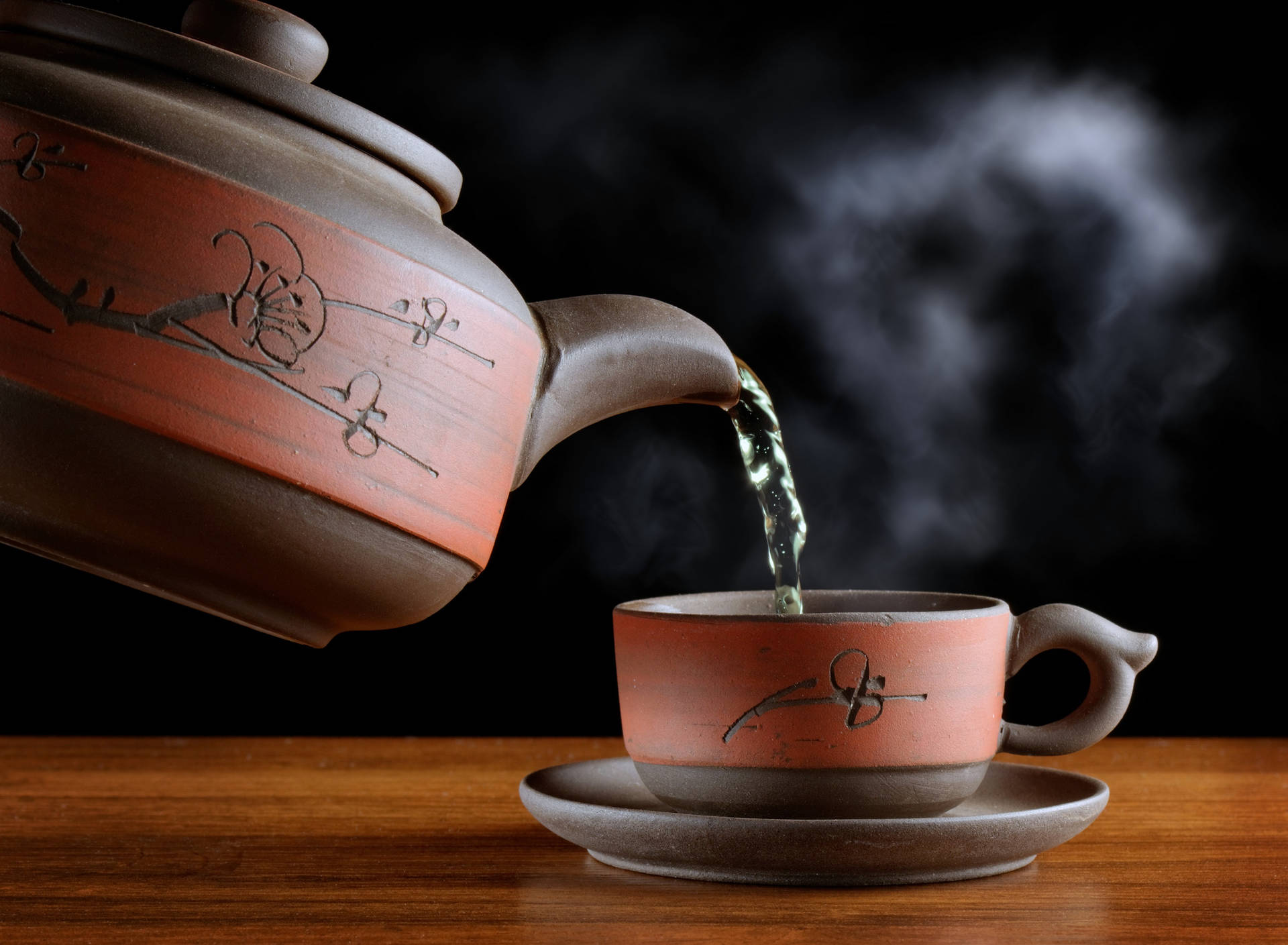 熱茶從陶瓷茶壺倒入木質表面上的相配茶杯中。
