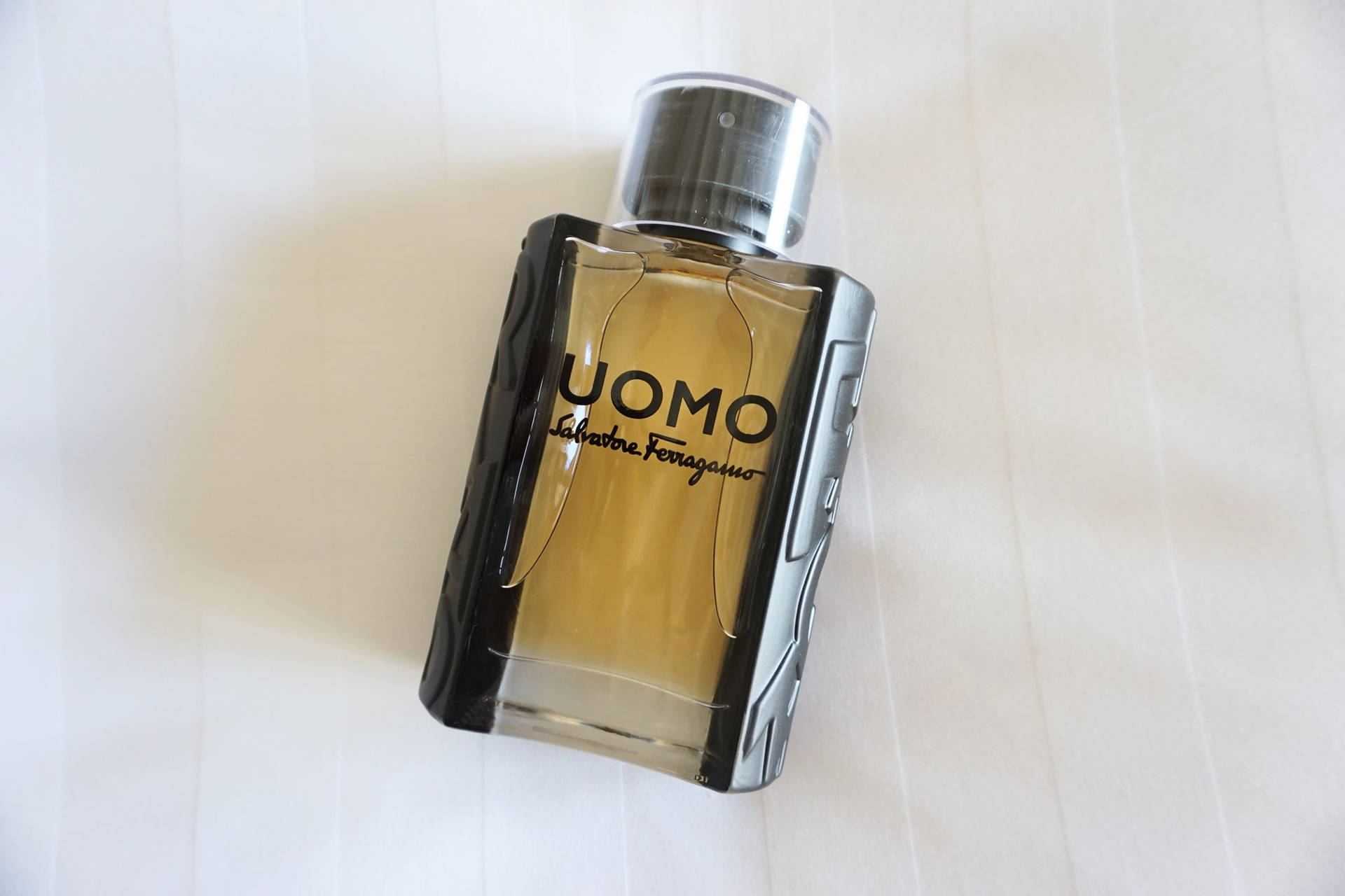 白色紋理背景上的 Salvatore Ferragamo UOMO 香水瓶