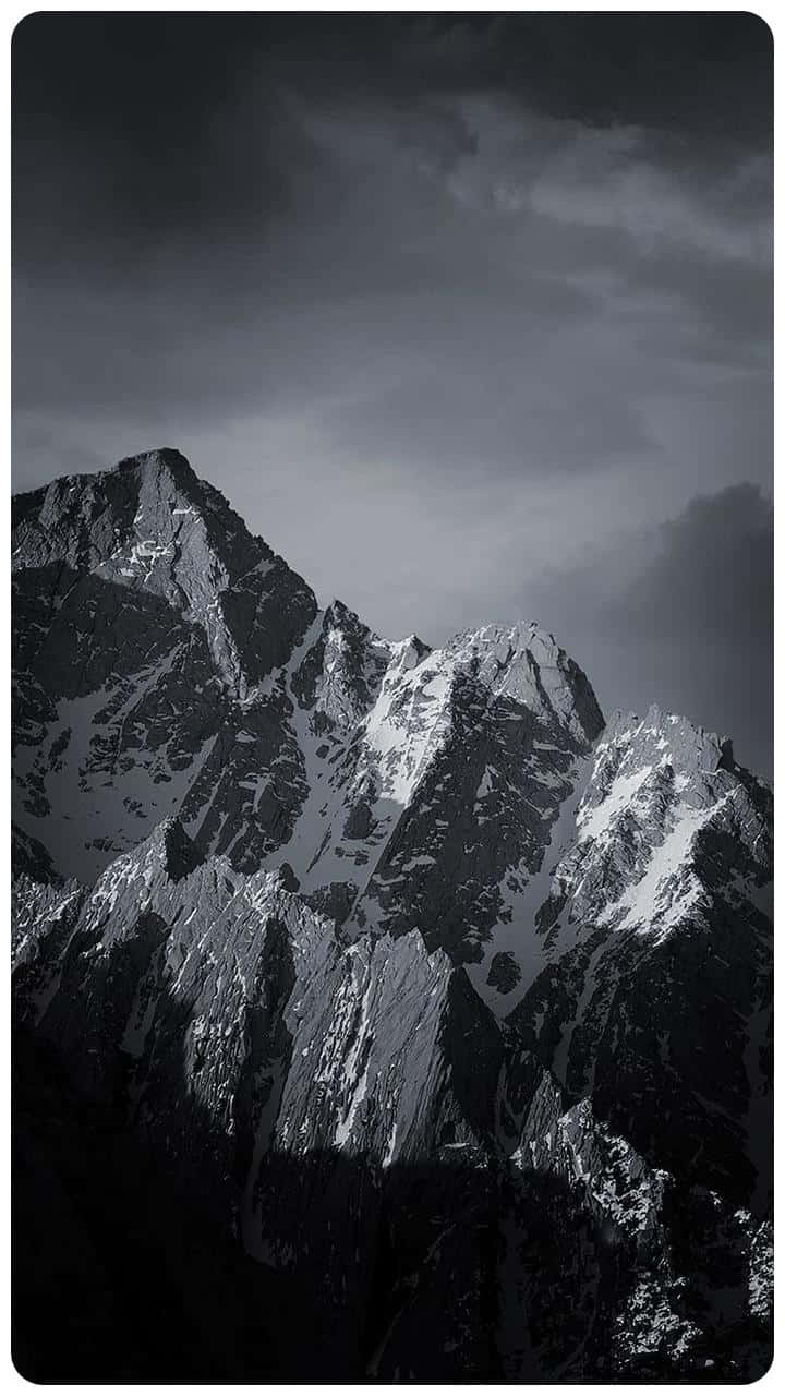 在黑暗的暴風雲下，黑白相間的積雪山峰。