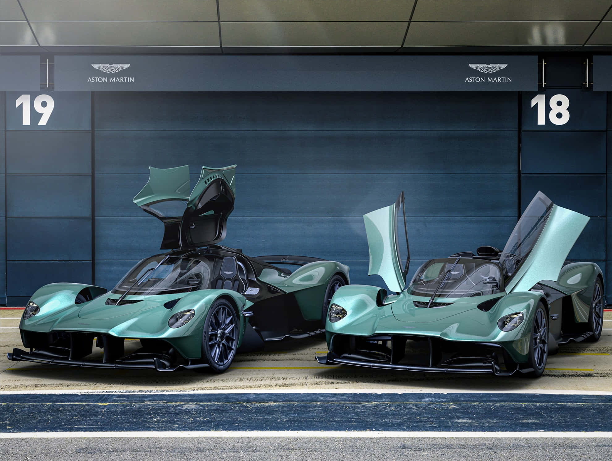 優雅駕馭，盡享奢華 壁紙 — 兩輛薄荷綠色Aston Martin超級跑車，鷗翼車門打開，停在有編號的車庫車位。