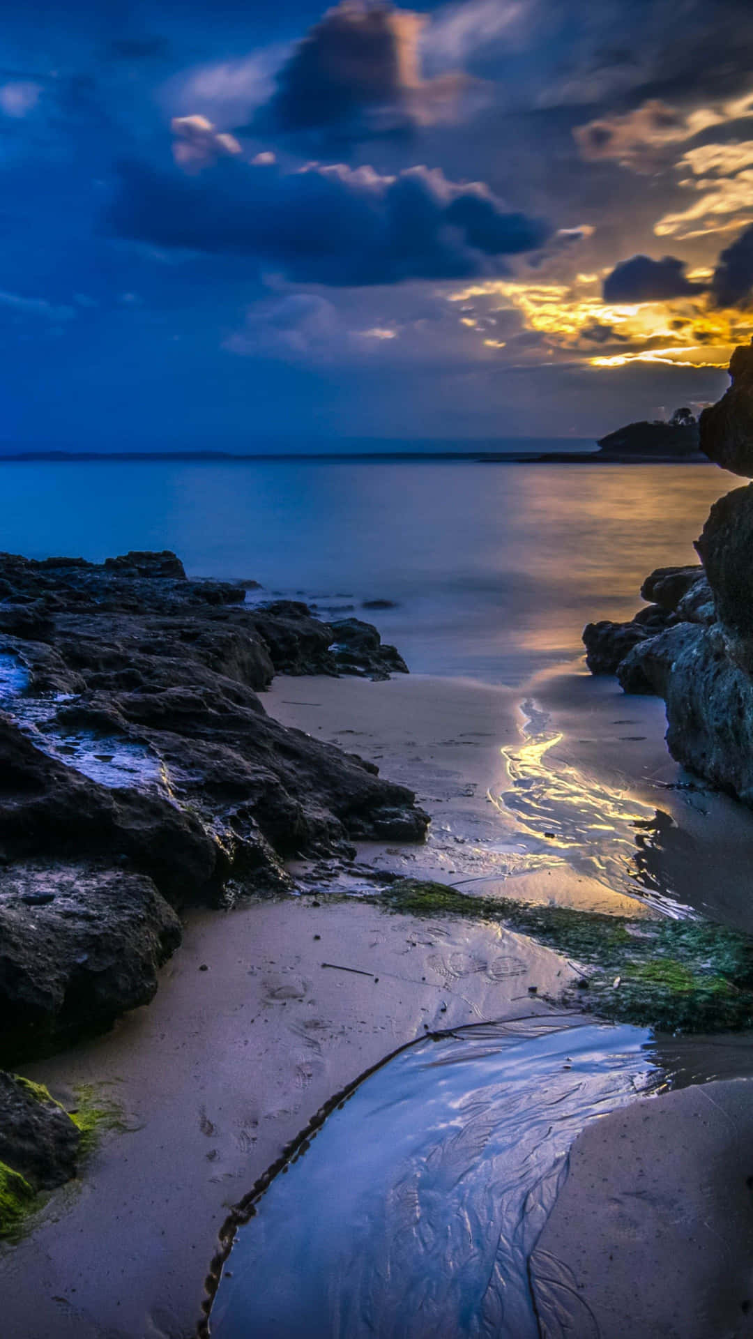 黃昏時分海洋上的夕陽，岩石和沙灘