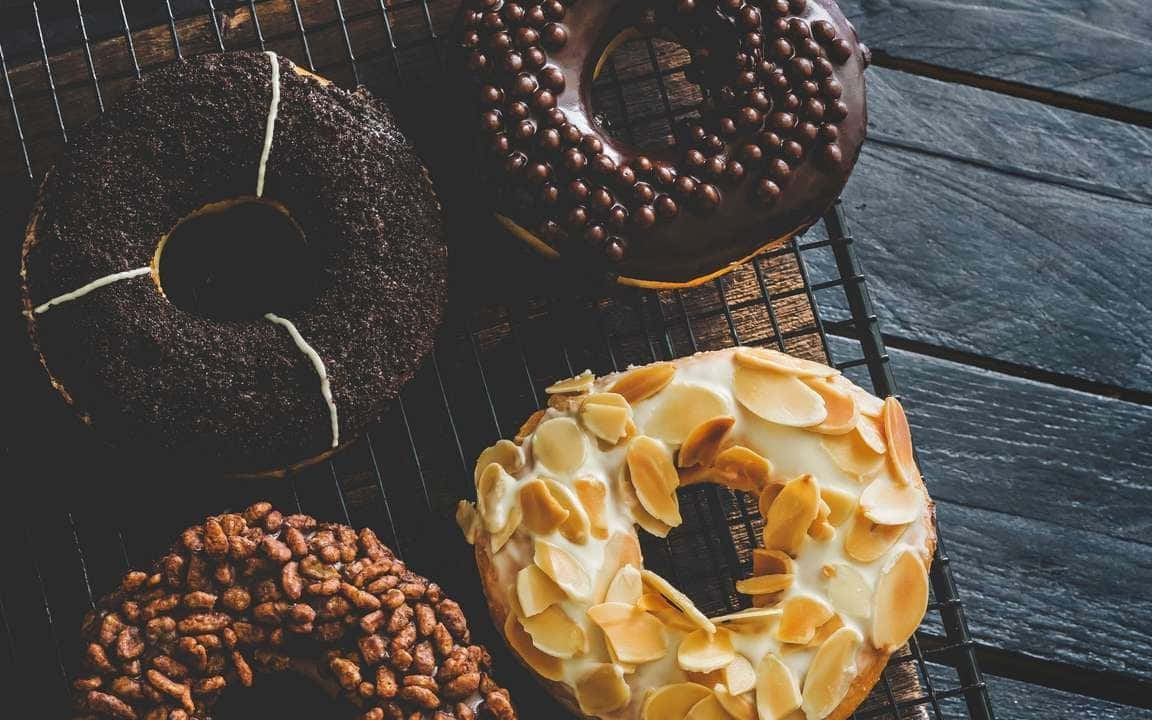 充滿愛意製作的美味糕點 壁紙 — 四個朱古力糖霜杏仁彩針冬甩放在深色木板上嘅金屬架上。