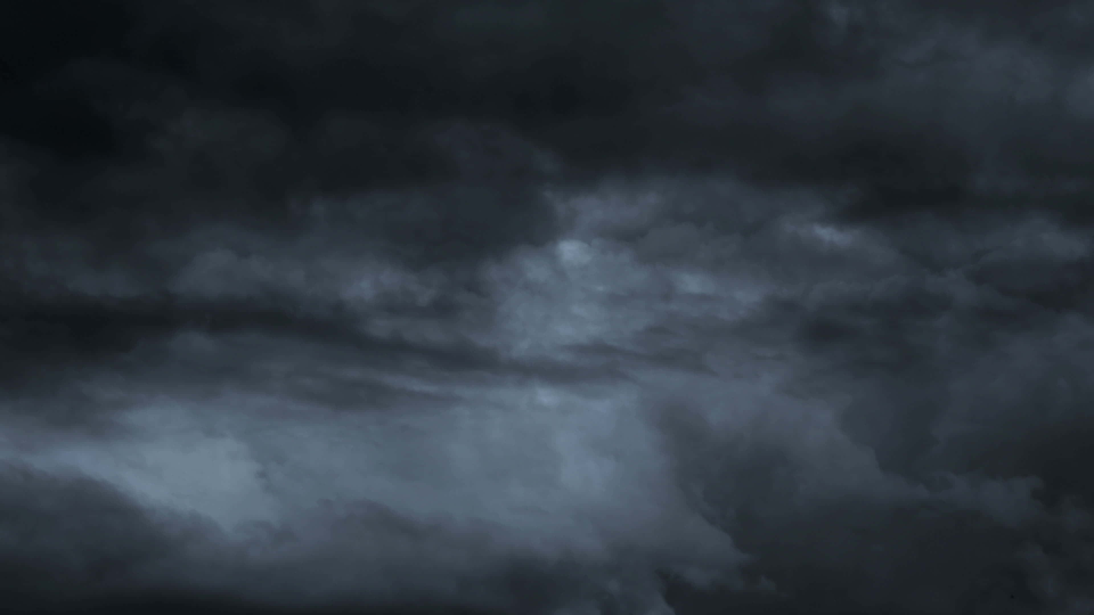 Dark Storm 桌布 壁紙 — 充滿戲劇性的天空，佈滿了在微弱月光下翻騰的深灰色雲層，營造出陰鬱的氛圍。