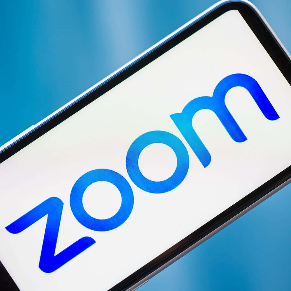 智能手機在藍色背景上顯示 Zoom 應用程式標誌。