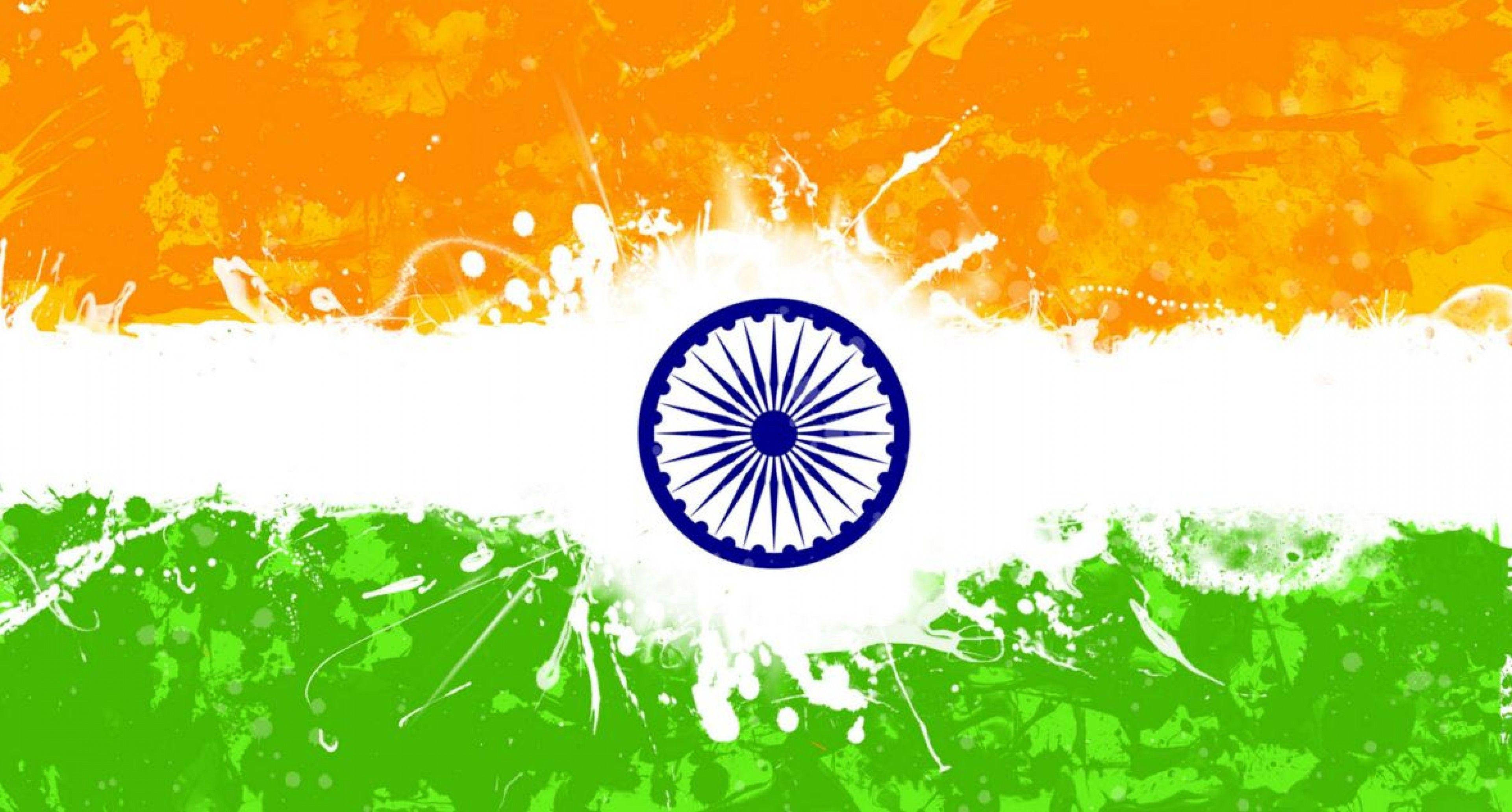 India 桌布 壁紙 — 充滿活力的印度國旗，帶有橙色、白色和綠色條紋，中央是藍色阿育王法輪，並有動態的顏料潑濺效果。