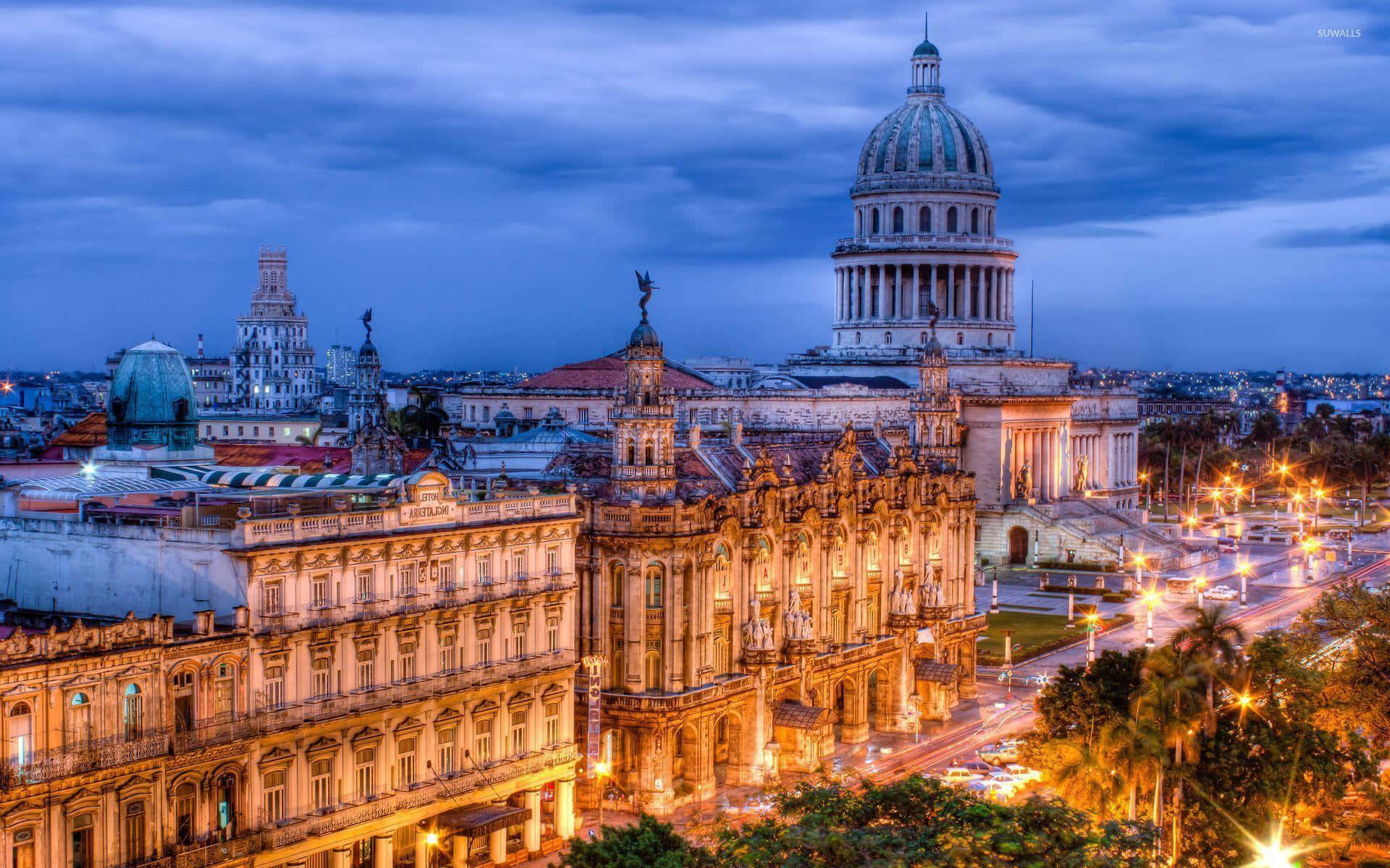 Cuba 桌布 壁紙 — 充滿活力的哈瓦那古巴暮色城市景觀，展現了在深藍色天空映襯下燈火通明的新古典主義建築和圓頂國會大廈。
