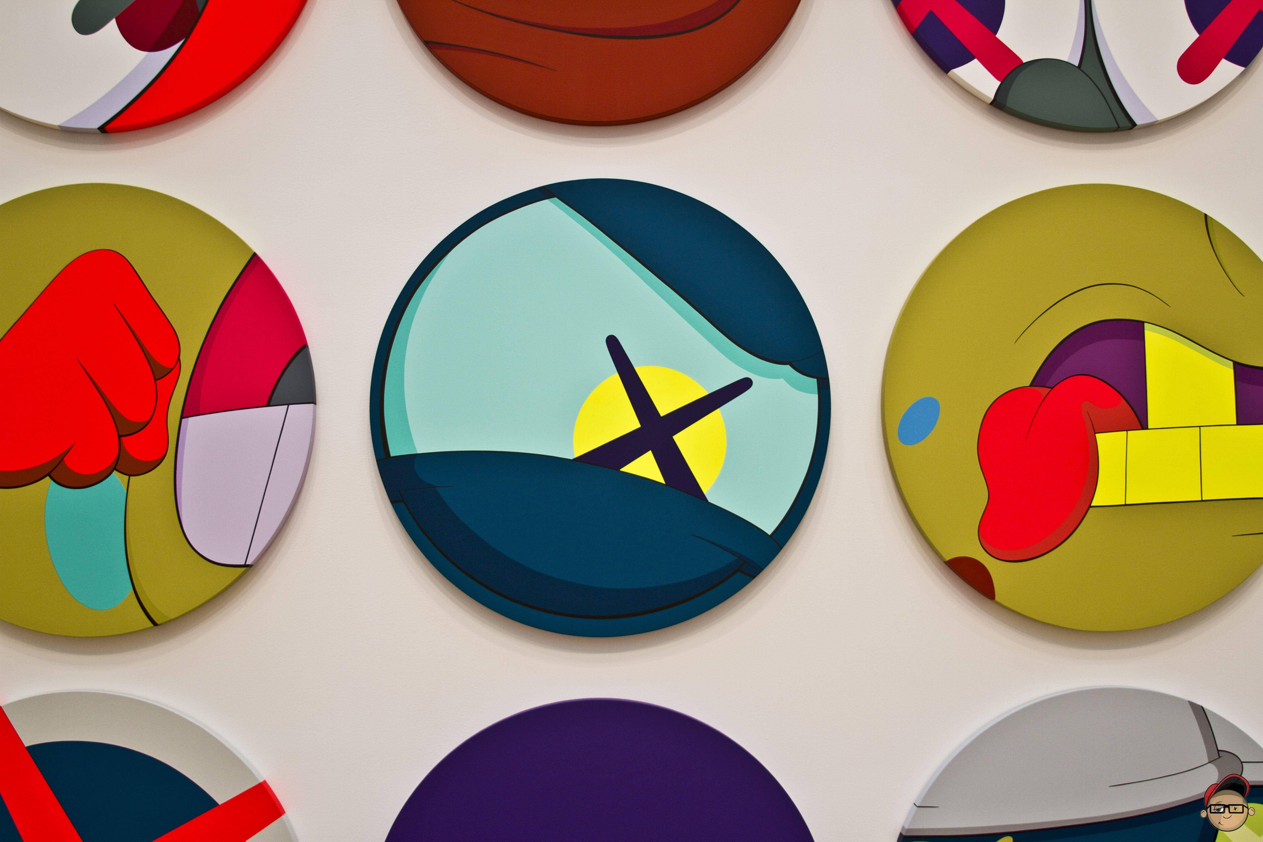 KAWS: Down Time 壁紙 — 充滿活力的圓形抽象藝術品，色彩大膽，幾何形狀，安裝在白色牆壁上。