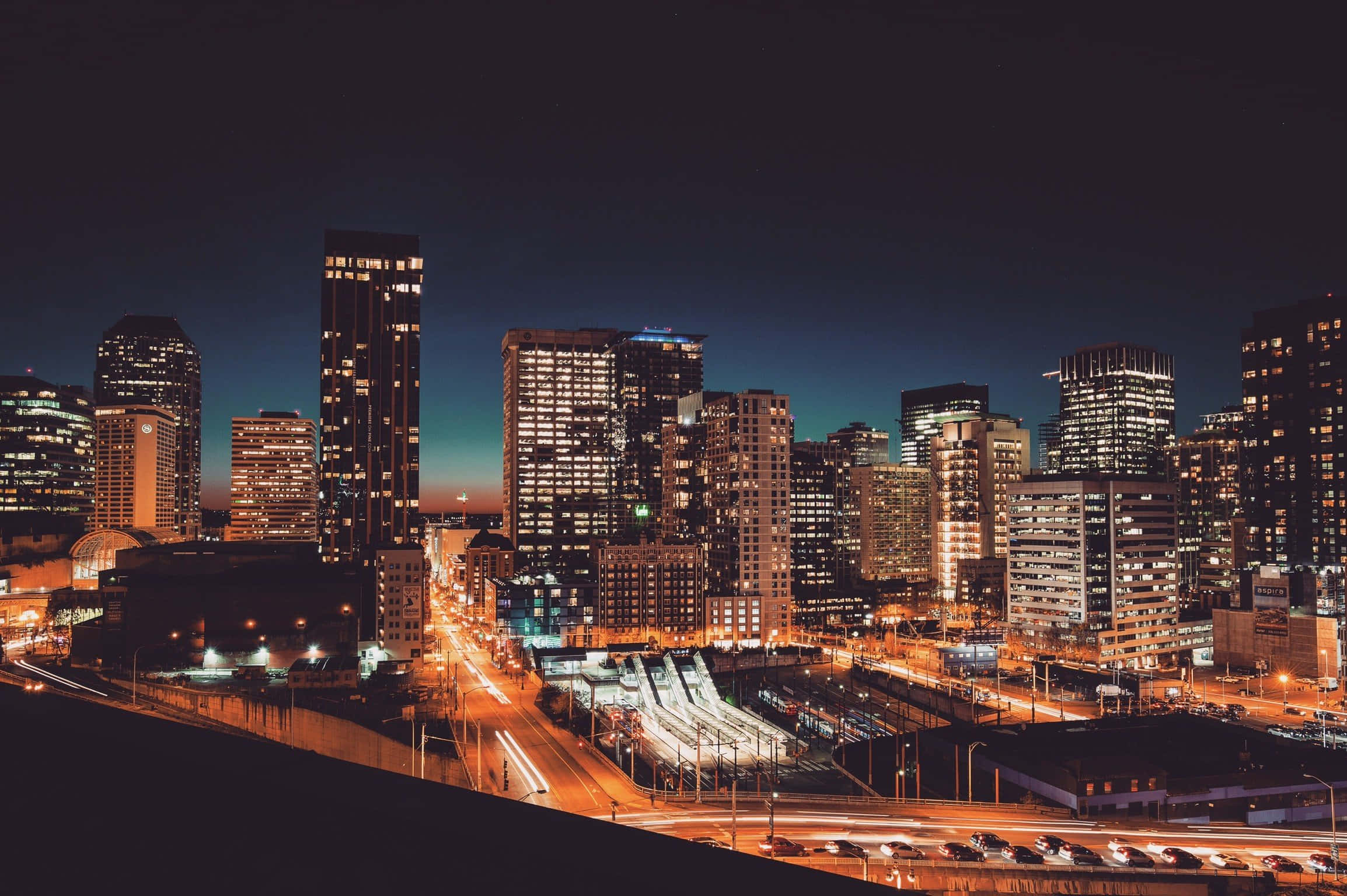 City Lights 桌布 壁紙 — 充滿活力的城市夜景，閃爍的摩天大樓和流動的交通燈光點亮了城市廣闊的空間。
