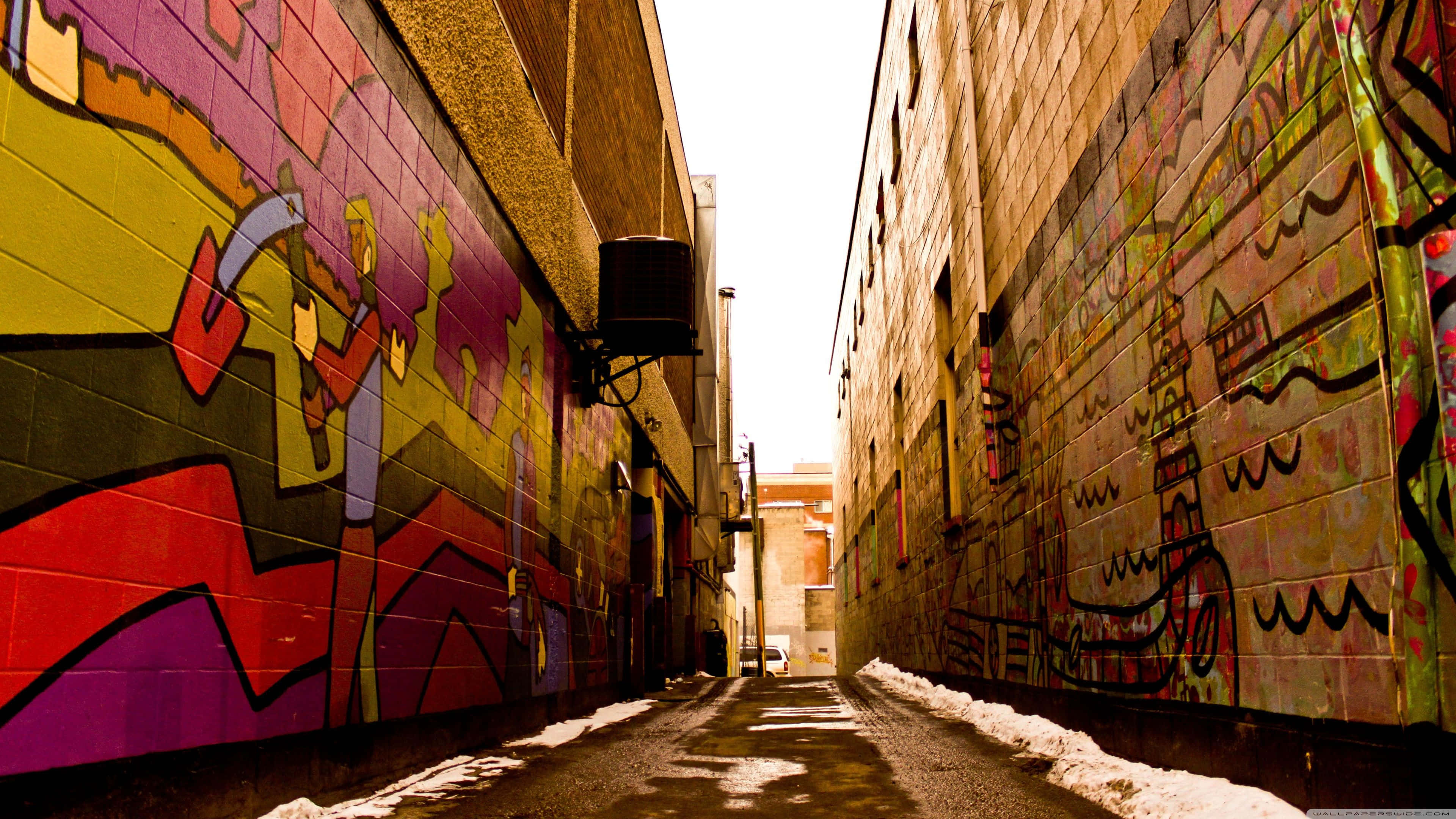 Alleyway 桌布 壁紙 — 充滿活力的塗鴉小巷，積雪的人行道和明亮的陽光照射的牆壁。