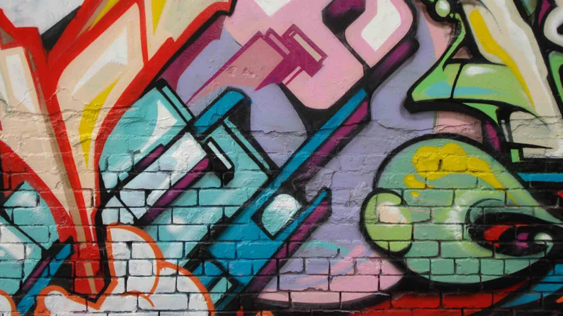 塗鴉 桌布 壁紙 — 充滿活力的塗鴉藝術在風化的磚牆上綻放，色彩大膽，動態抽象形狀。