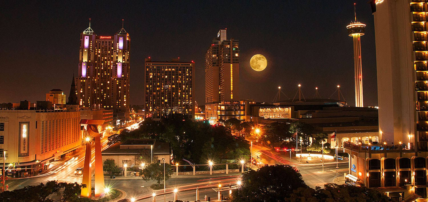 Buildings 桌布 壁紙 — 充滿活力的夜景城市景觀，閃爍的摩天大樓和一輪滿月在繁忙街道上方升起，伴隨著光跡。