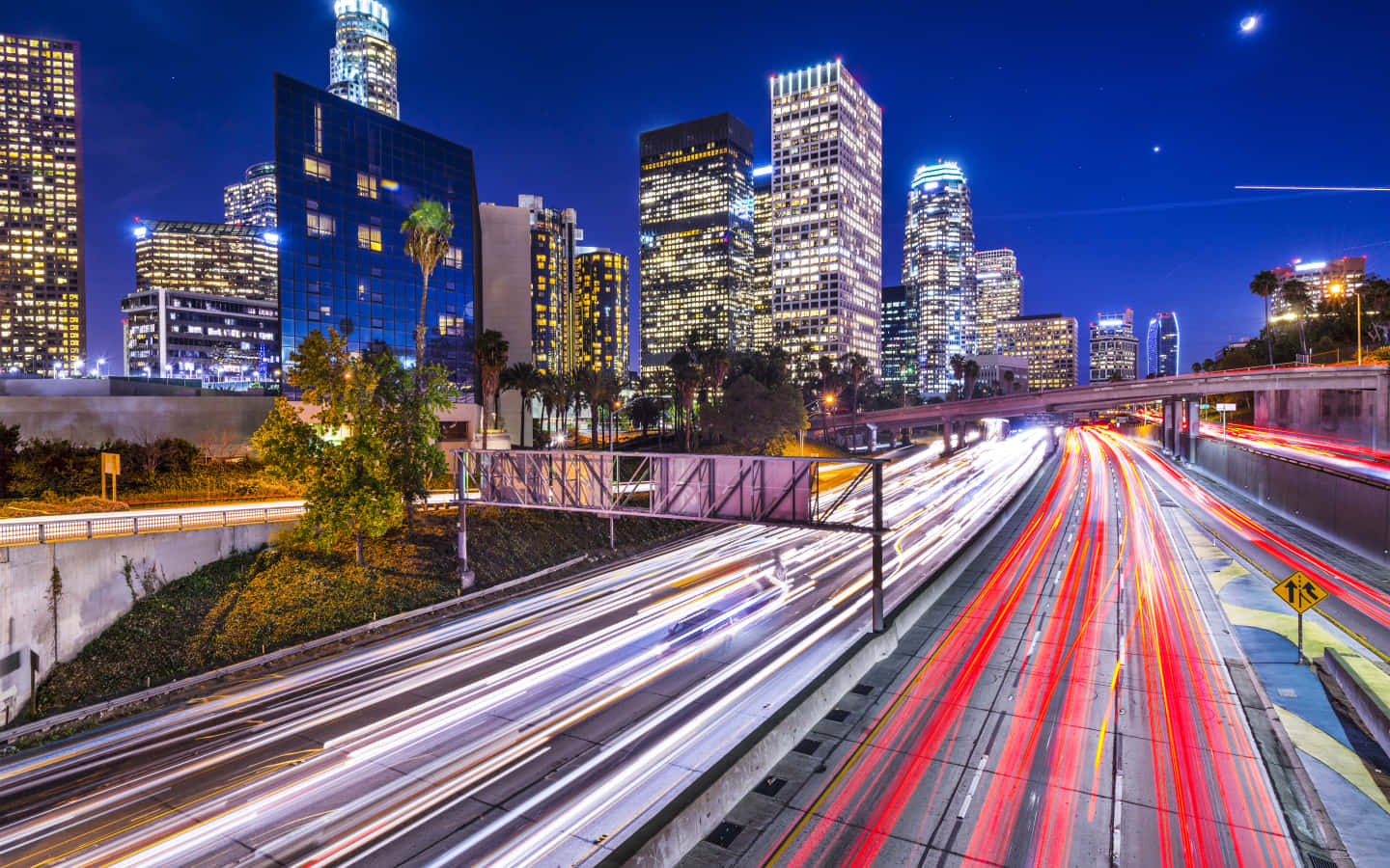 La 桌布 壁紙 — 充滿活力的夜景城市景觀，高聳的摩天大樓下高速公路上的車流形成光軌。