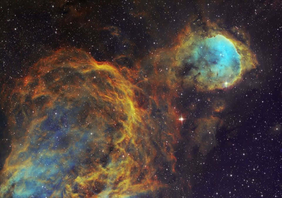 Interstellar Cloud 桌布 壁紙 — 充滿活力的宇宙星雲在繁星點點的黑暗虛空中散發出火熱的橙色和冷藍色調。