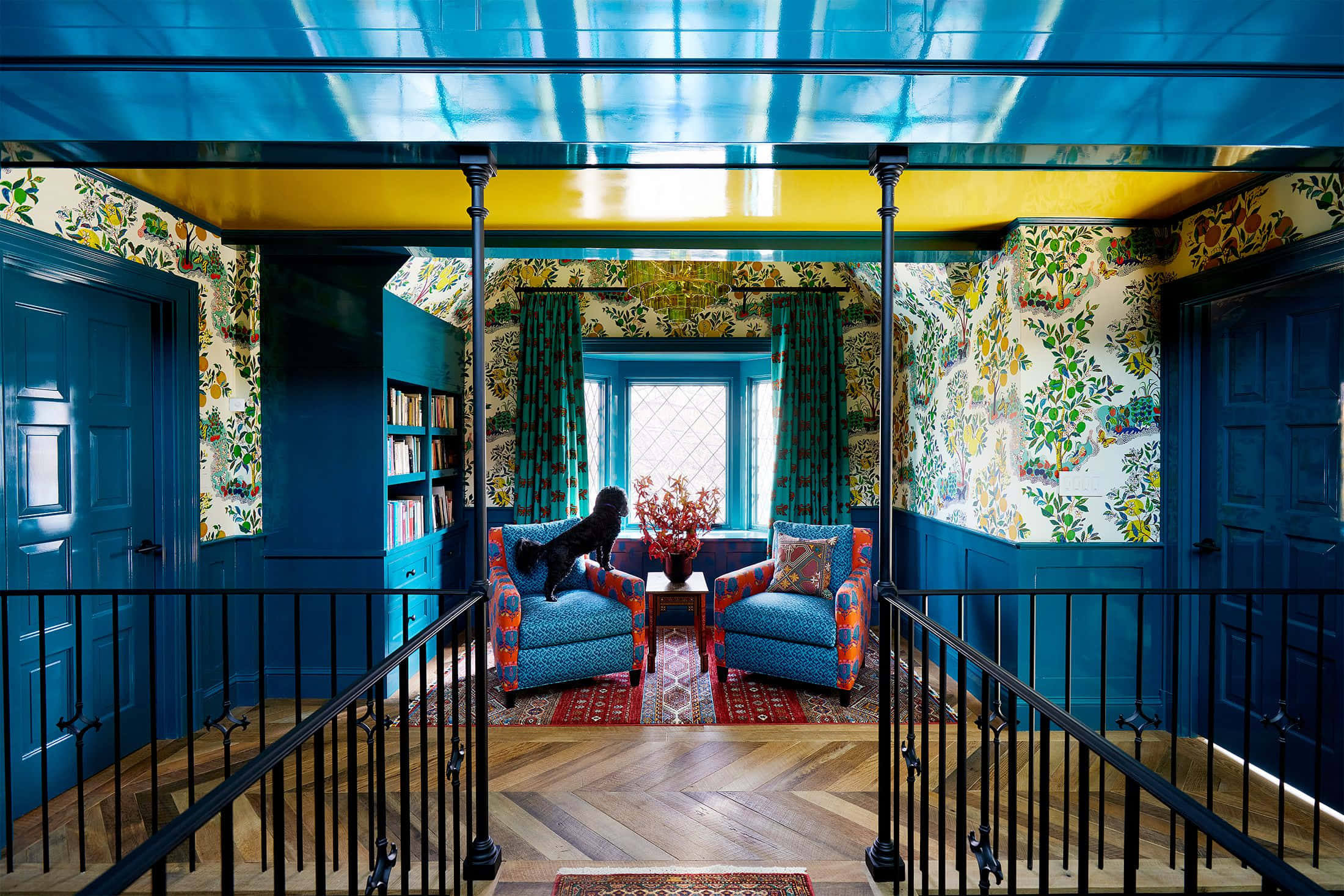 Interior Design 桌布 壁紙 — 充滿活力的室內設計，大膽的藍色牆壁、花卉壁紙和一隻黑狗棲息在圖案扶手椅上。