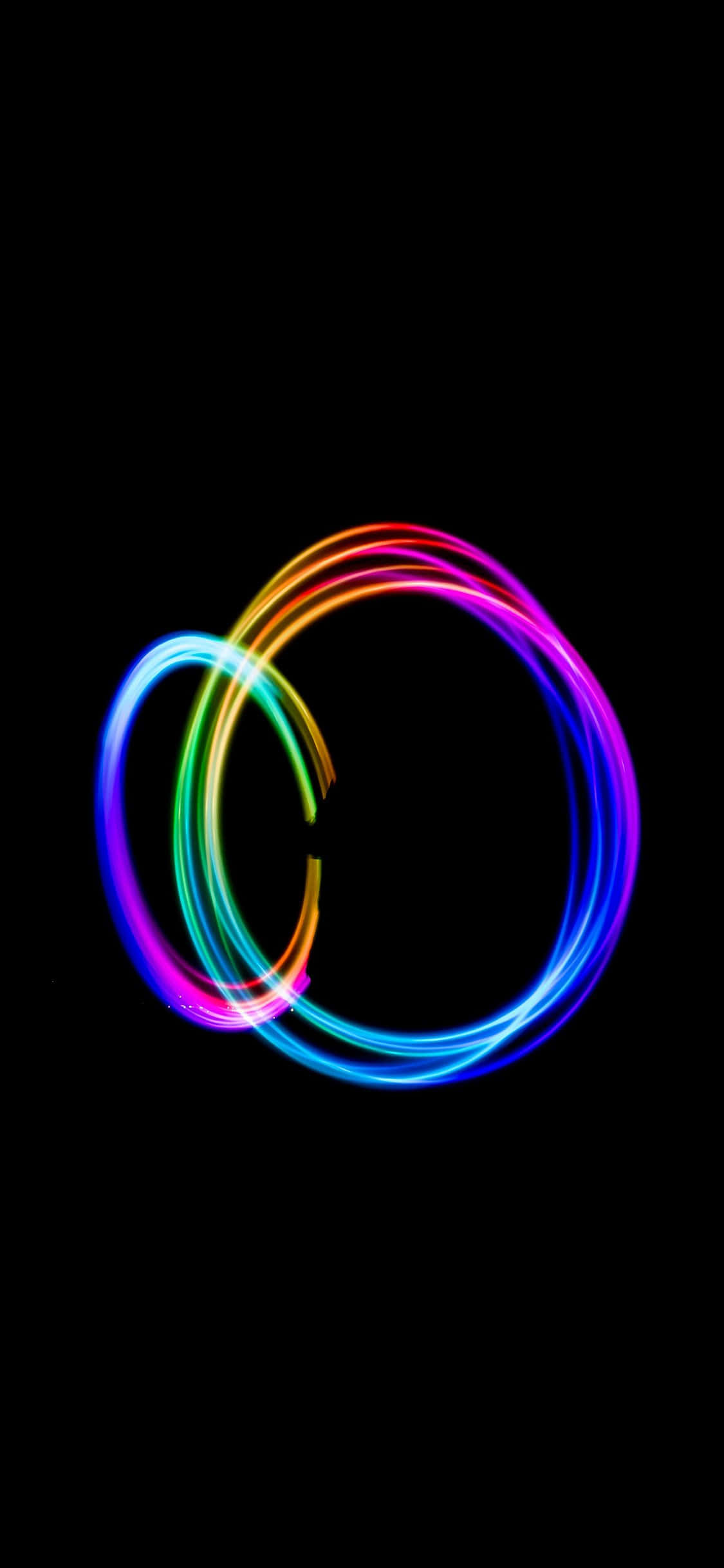 Dark Circles 桌布 壁紙 — 充滿活力的彩虹光軌在純黑色背景上旋轉成重疊的圓圈。