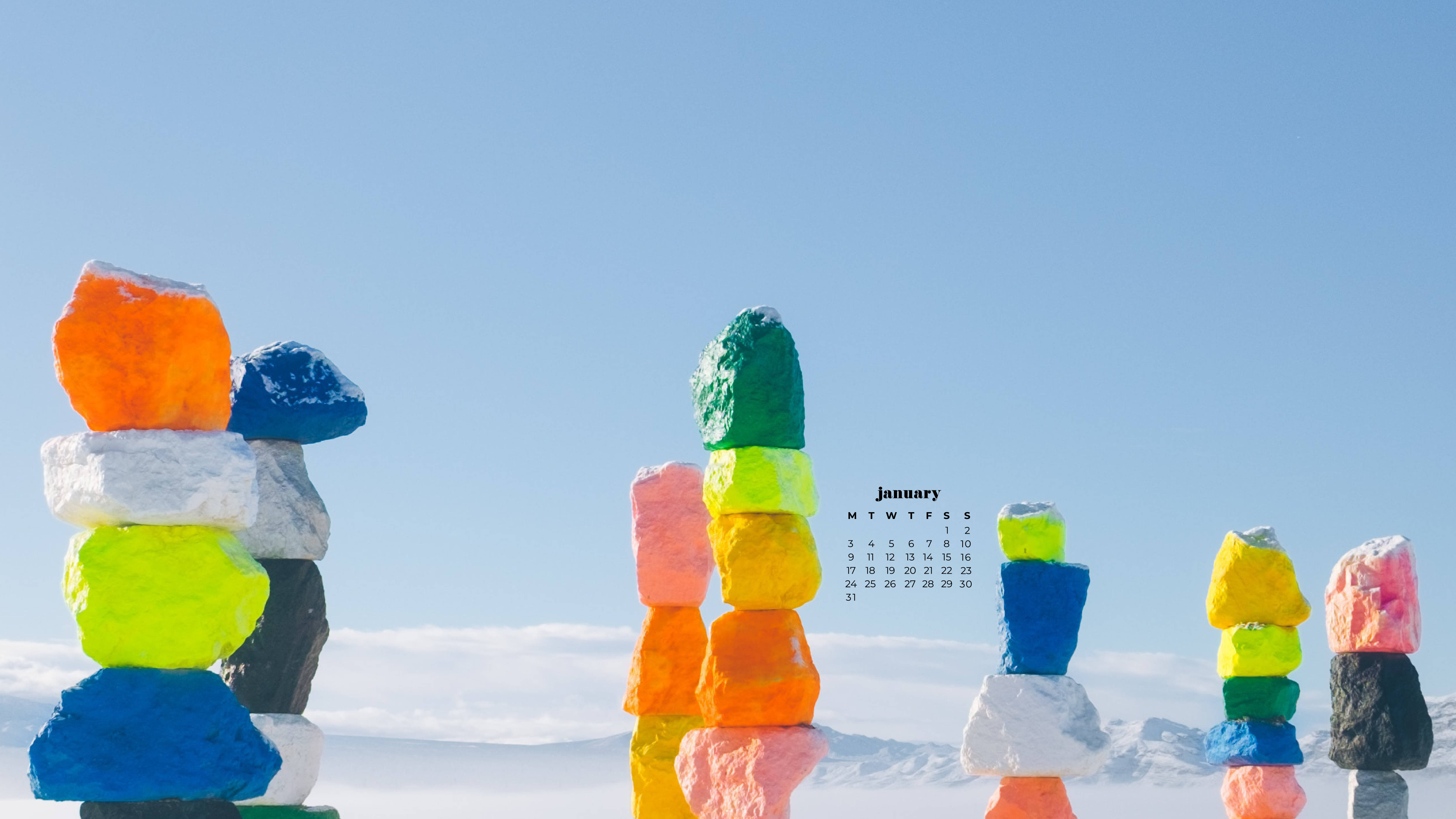雪 桌布 壁紙 — 充滿活力的彩虹色堆疊石塊在晴朗的藍天下高高聳立，並帶有1月日曆疊加層。