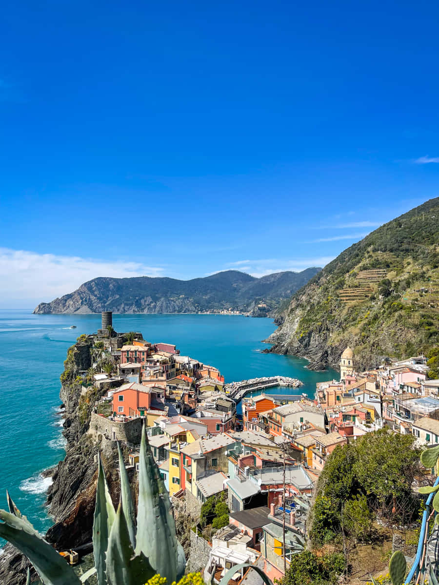 Italian Beach 桌布 壁紙 — 充滿活力的懸崖村莊，色彩繽紛的房屋矗立在碧綠的海面上，天空清澈湛藍。