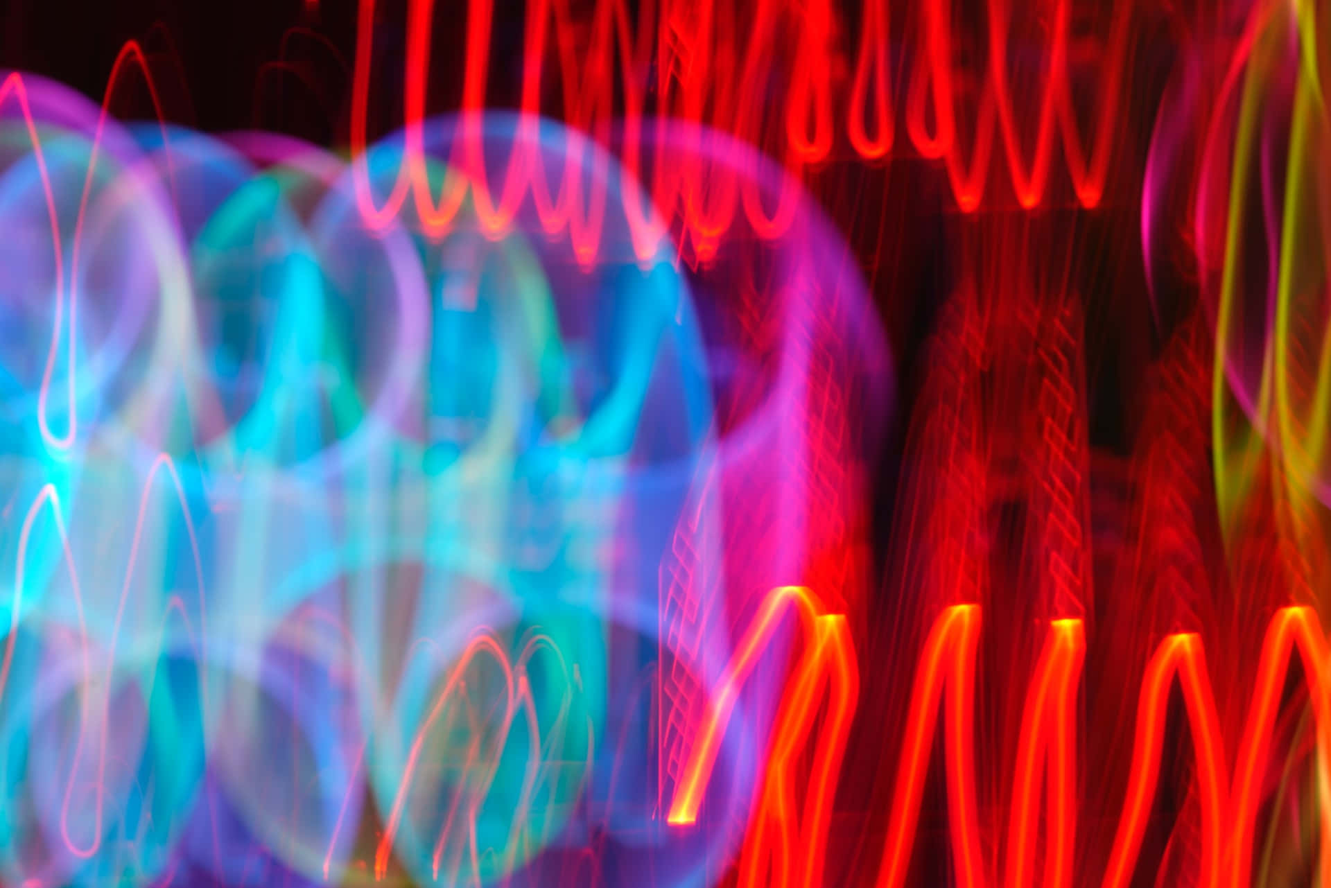 Psychedelic Neon Lights 桌布 壁紙 — 充滿活力的抽象光軌在深色背景上以電光紅、藍和紫色旋轉。