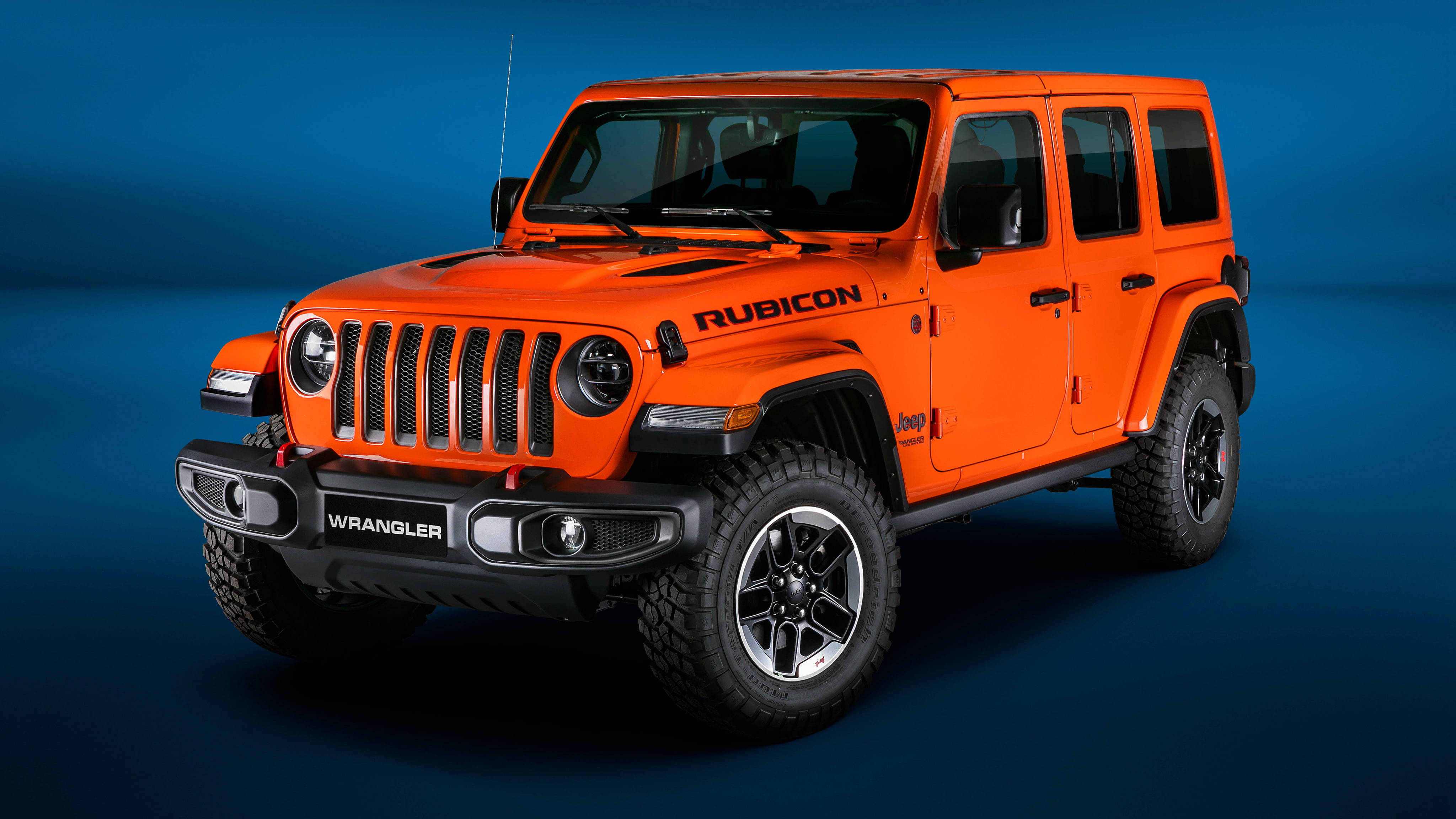 橙色動態圖 桌布 壁紙 — 充滿活力的橙色Jeep Wrangler Rubicon在深藍色工作室背景前，配合戲劇性燈光，大膽地矗立。