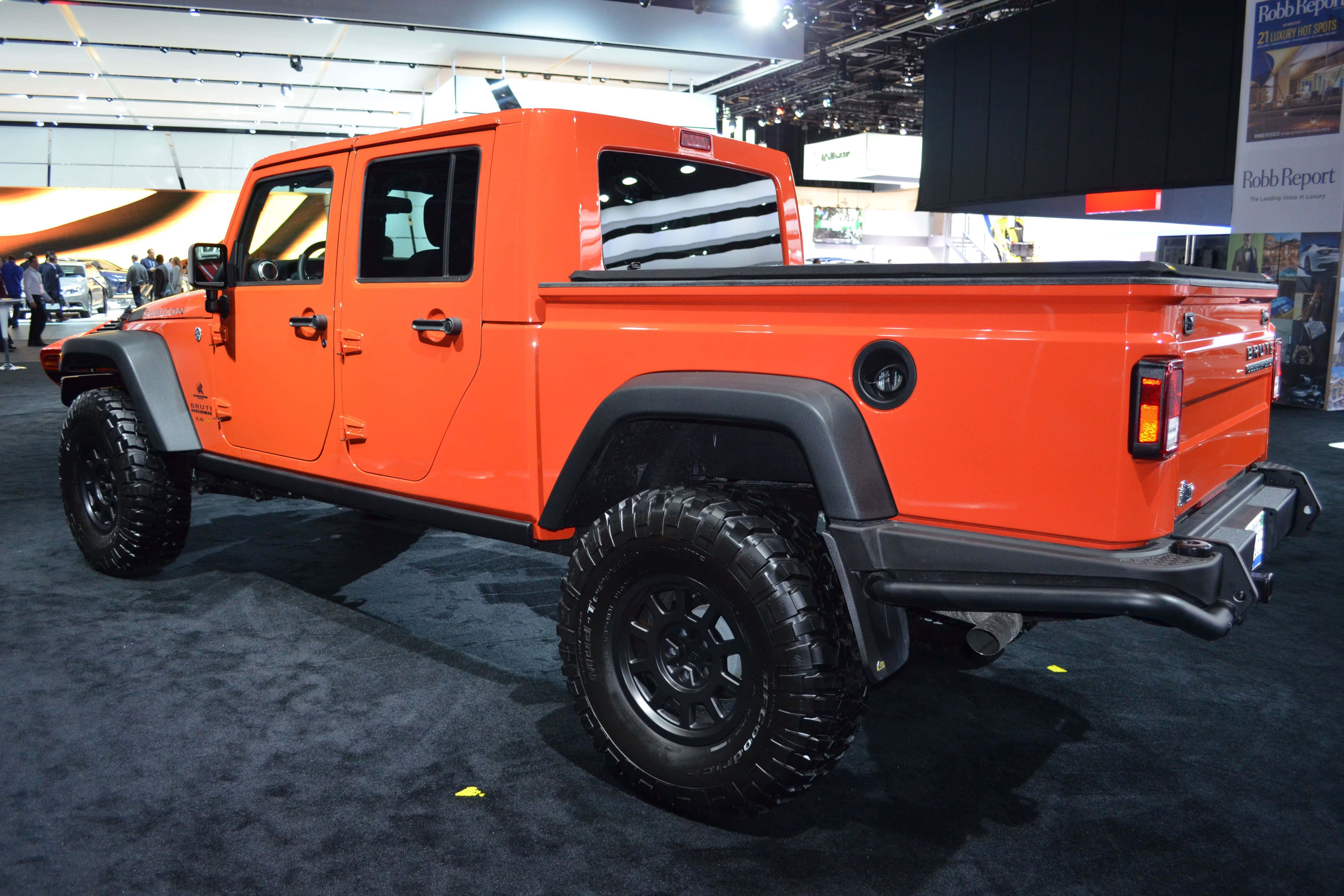 Jeep Gladiator 桌布 壁紙 — 充滿活力的橙色Jeep皮卡車在車展上展出，配備黑色輪胎和堅固設計。