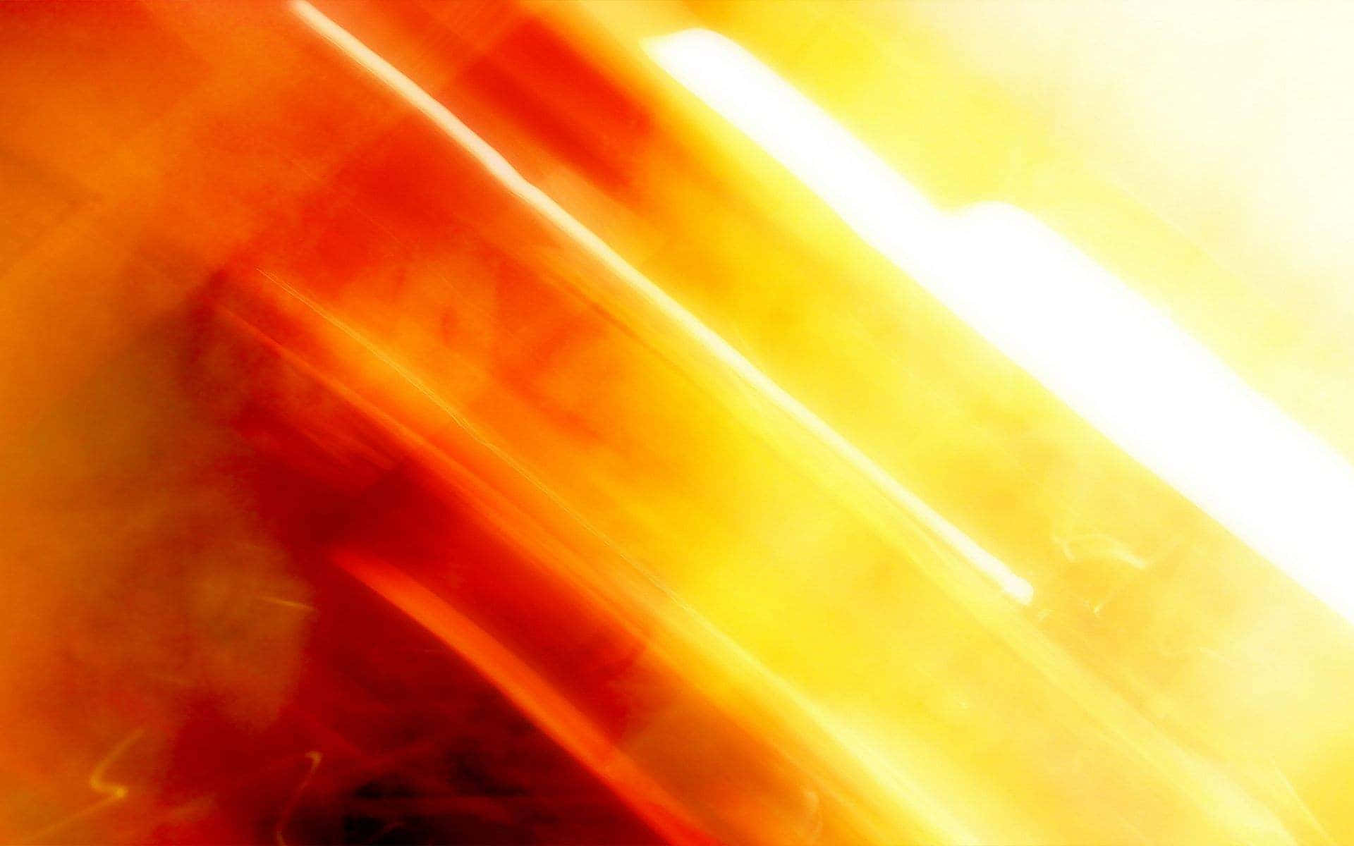 Orange And Yellow 桌布 壁紙 — 充滿活力的橙色和黃色光線的抽象條紋對角線模糊穿過畫面，營造出動態的能量光芒。