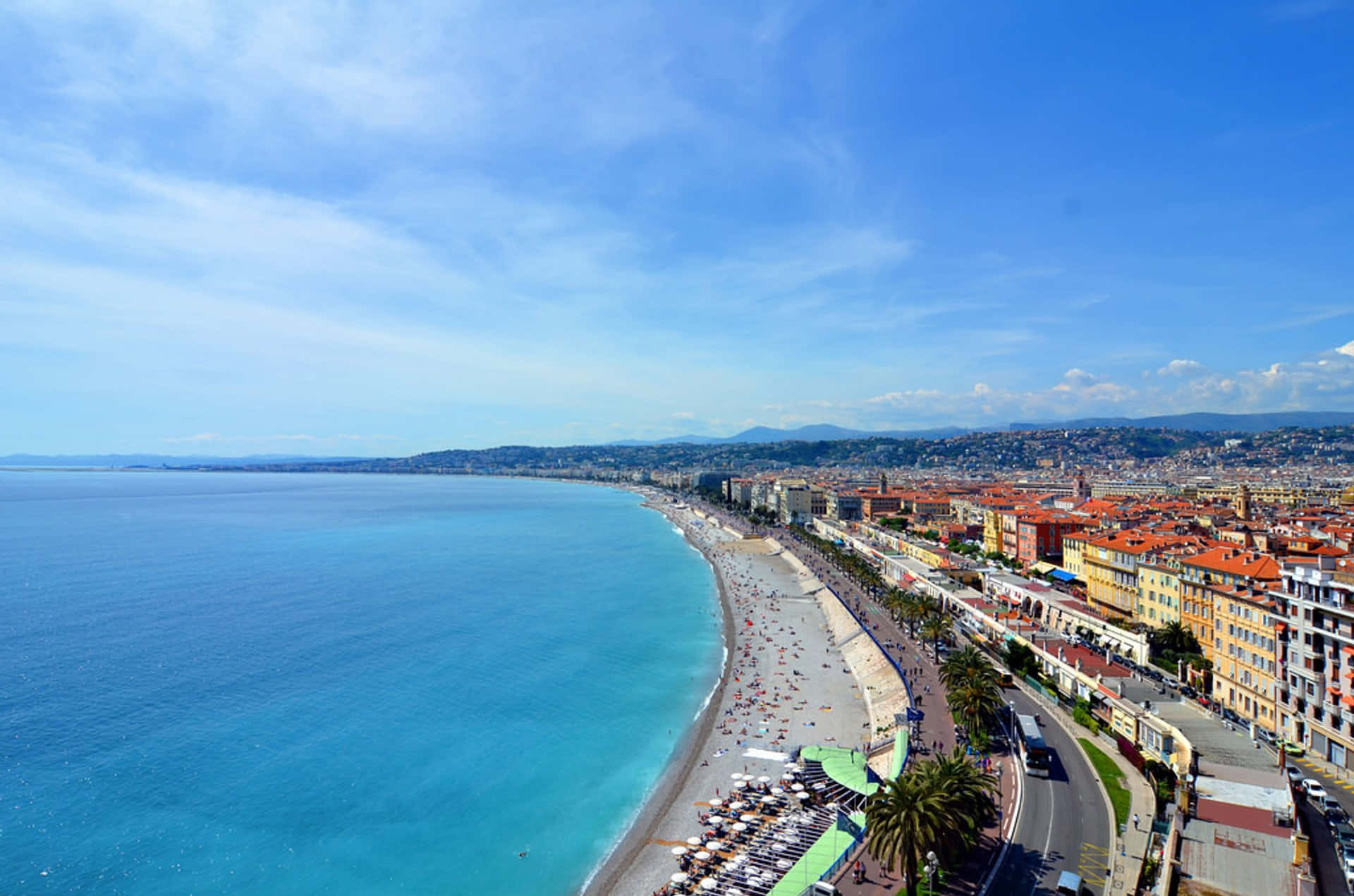 French Beach 桌布 壁紙 — 充滿活力的沿海城市的鳥瞰圖，擁有碧綠色的海水、沙灘和色彩繽紛的建築，在明亮的藍天下。