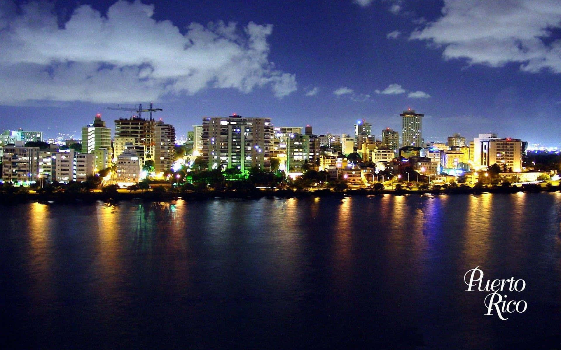 波多黎各 桌布 壁紙 — 充滿活力的波多黎各夜景，發光的建築物倒映在平靜的水面上，天空多雲。