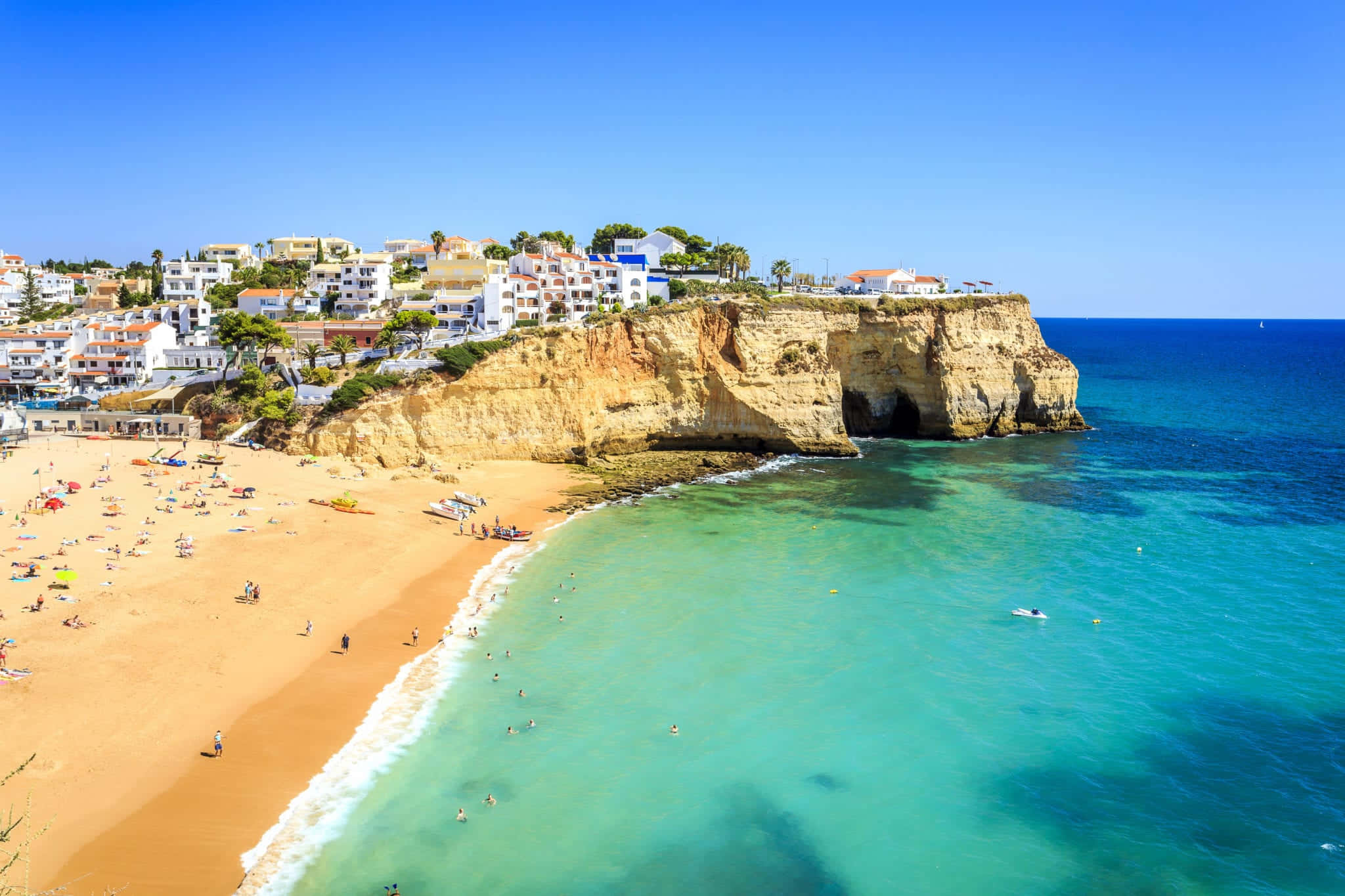 Portuguese Beach 桌布 壁紙 — 充滿活力的海岸景色，碧綠的海水拍打著金色沙灘，上方是清澈的藍天。
