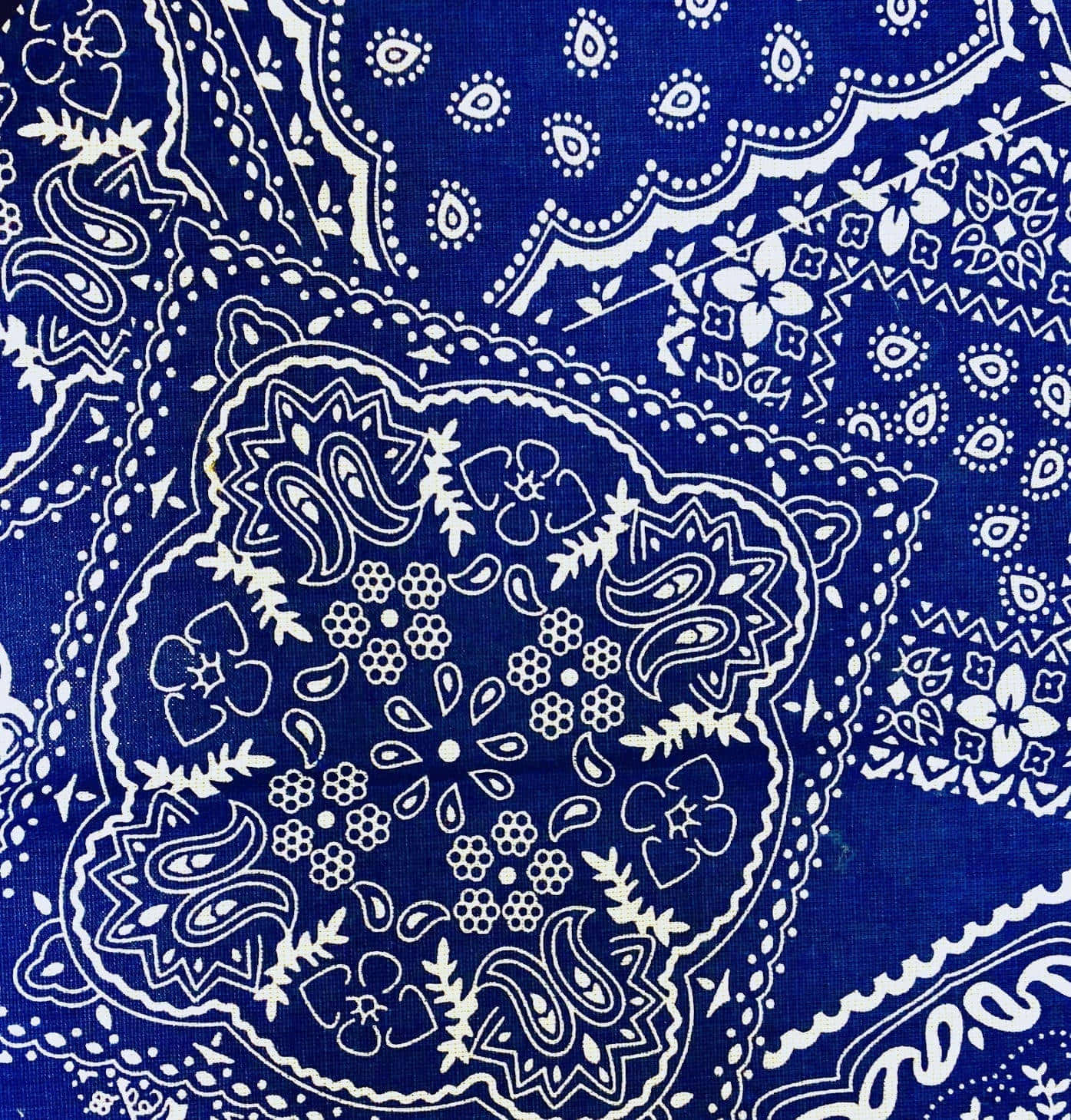 bandana 桌布 壁紙 — 充滿活力的皇家藍色布料，飾有複雜的白色佩斯利花卉圖案和扇形邊緣。