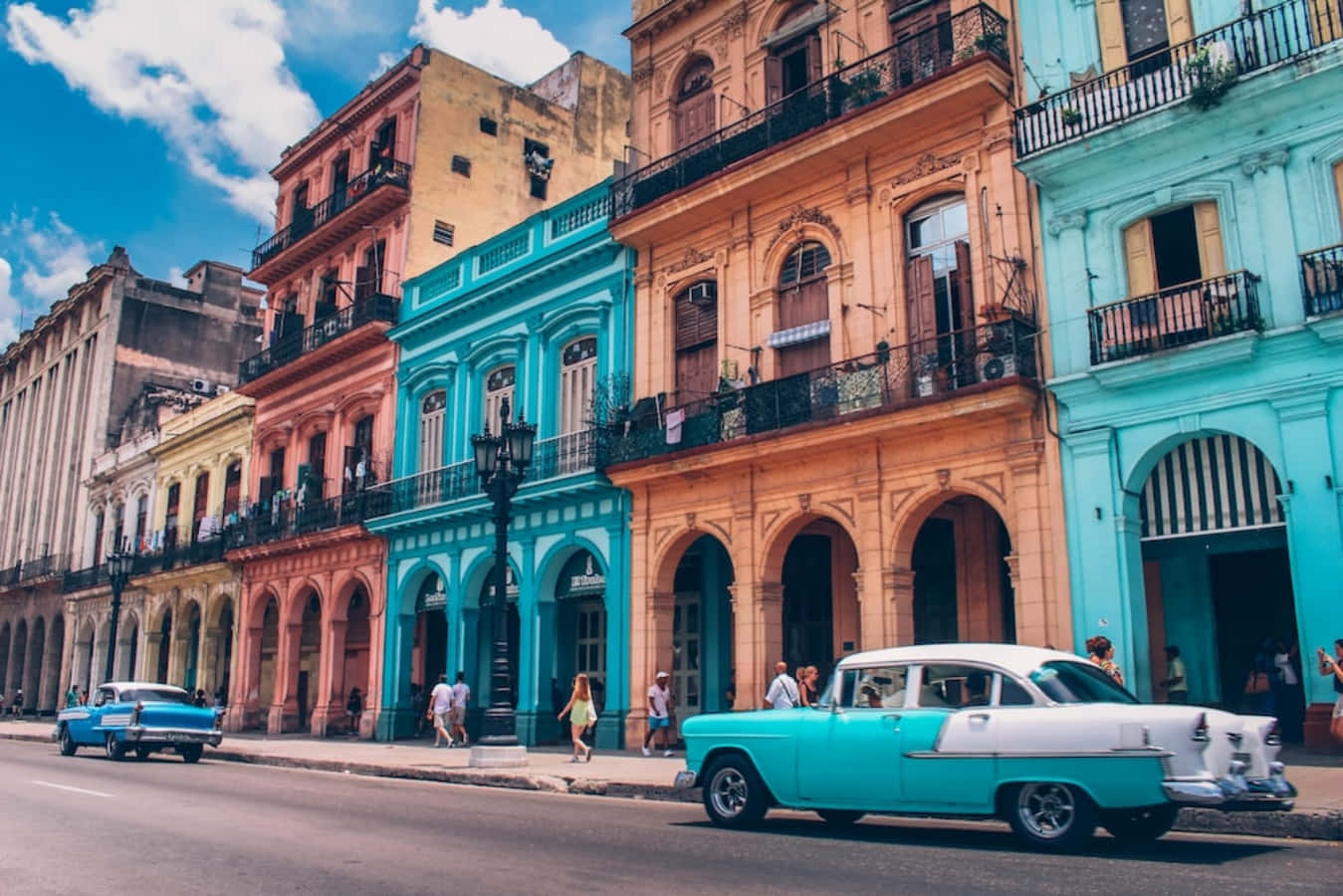 Cuba 桌布 壁紙 — 充滿活力的粉彩殖民建築排列在陽光明媚的街道上，伴隨著經典的美國汽車和行人，位於古巴哈瓦那。