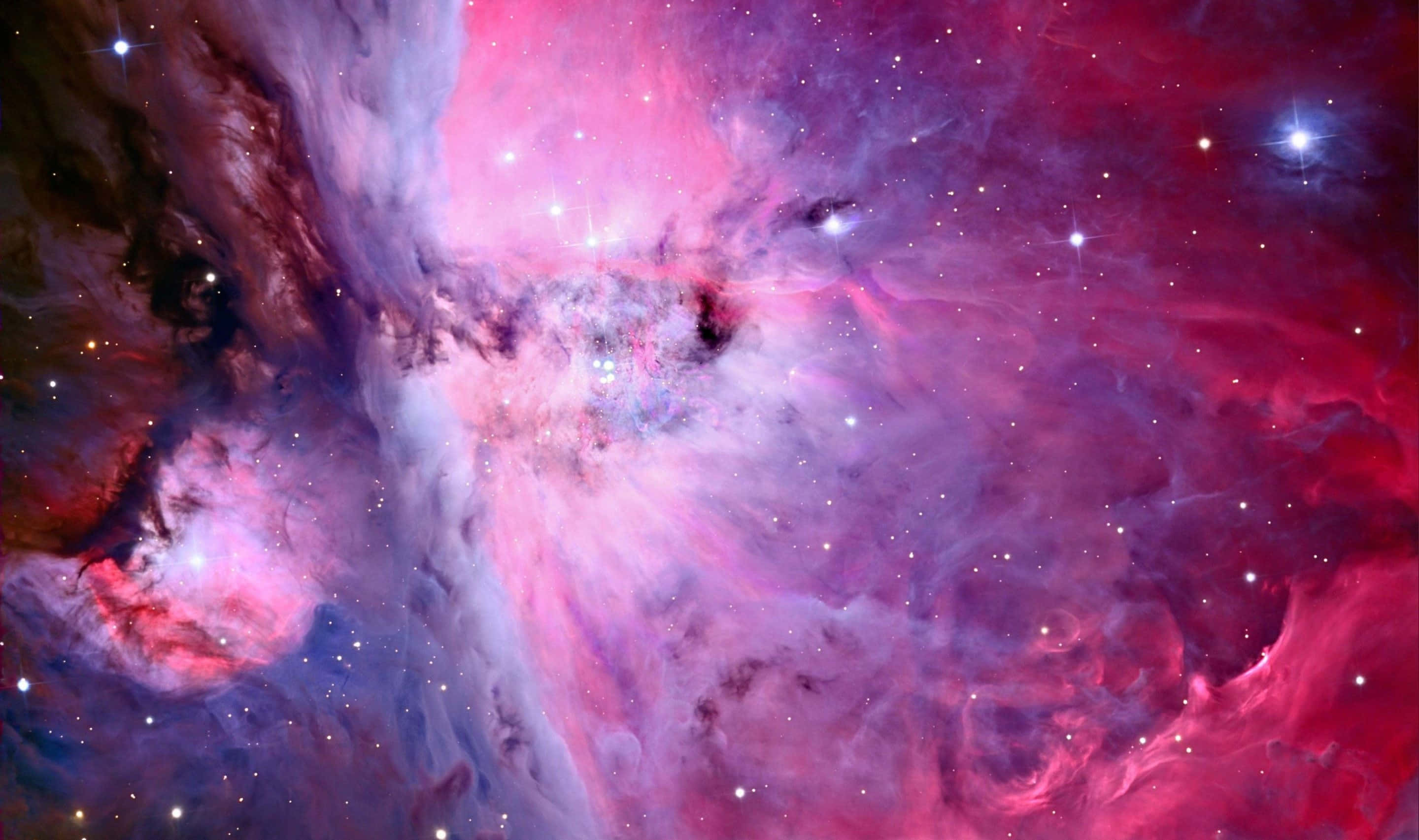 Pink Galaxy 桌布 壁紙 — 充滿活力的粉紅色、紫色和藍色宇宙雲層與發光的星星在令人嘆為觀止的星雲場景中旋轉。