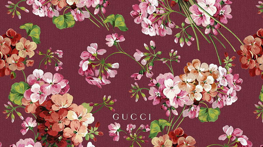 Gucci 桌布 壁紙 — 充滿活力的粉紅蜜桃和珊瑚色天竺葵在帶有細緻Gucci標誌水印的質感酒紅色布料上盛開。