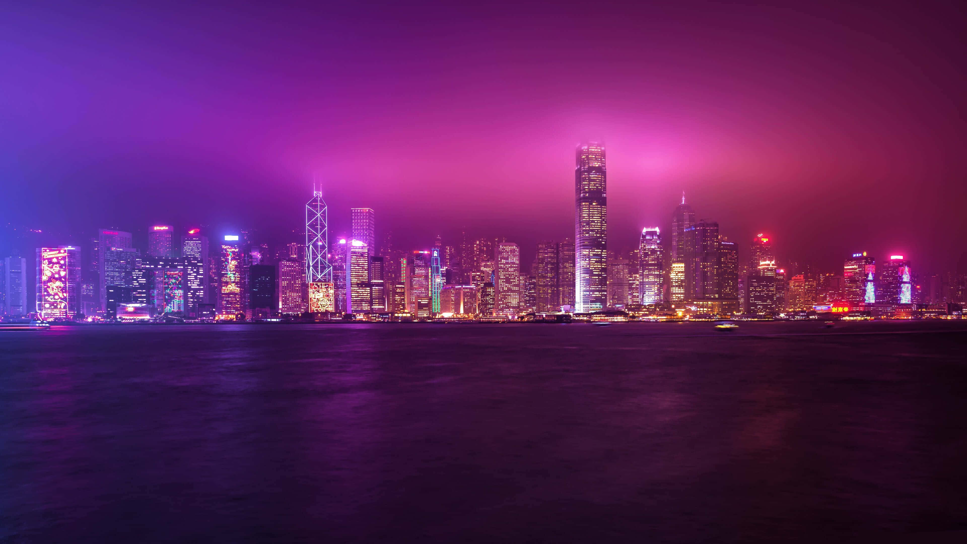 4K Display 桌布 壁紙 — 充滿活力的紫色調城市天際線夜景，發光的摩天大樓倒映在平靜的水面上。