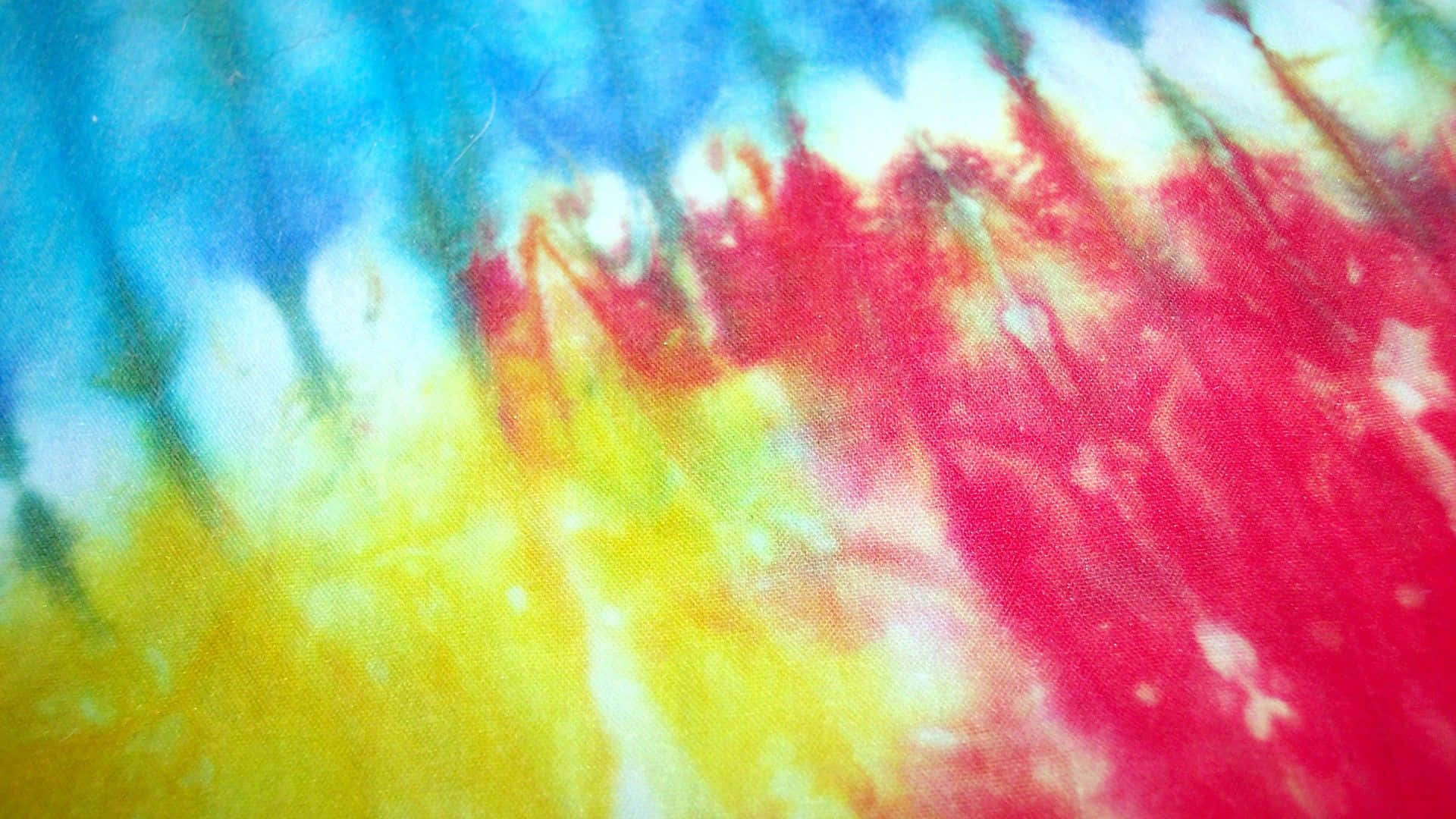 Pastel Tie Dye 桌布 壁紙 — 充滿活力的紮染布料以鮮明的紅、黃、藍、白色漩渦，營造出迷幻的抽象圖案。