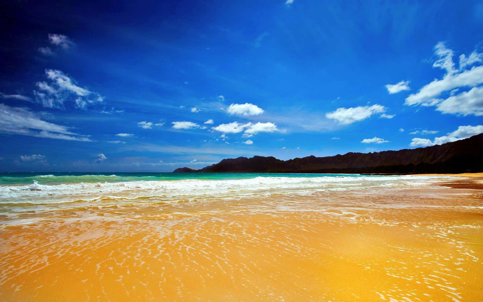 Yellow Beach 桌布 壁紙 — 充滿活力的綠松石色海浪拍打著金色沙灘，上方是湛藍的天空，點綴著幾朵白雲。