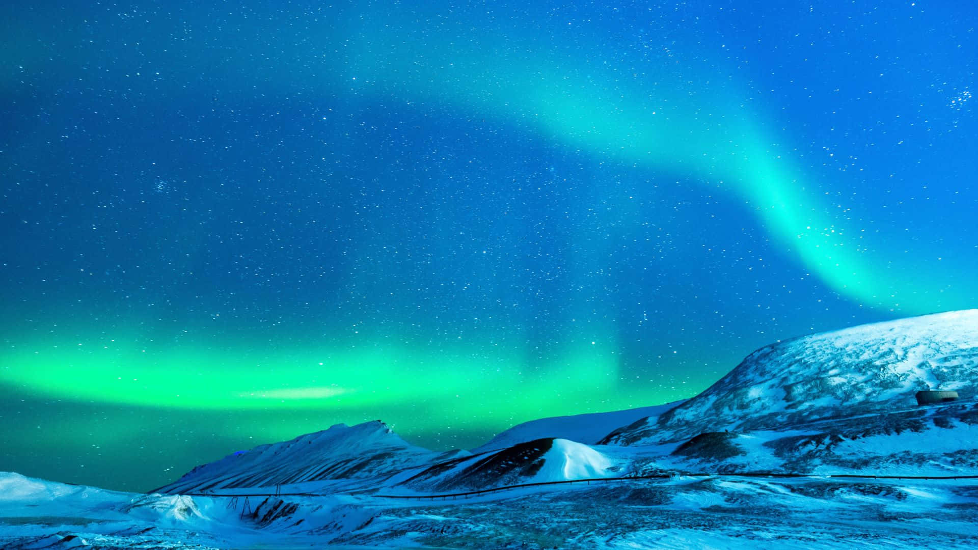 aurora borealis 桌布 壁紙 — 充滿活力的綠色北極光在繁星點點的夜空中舞動，照耀著白雪覆蓋的北極山脈。