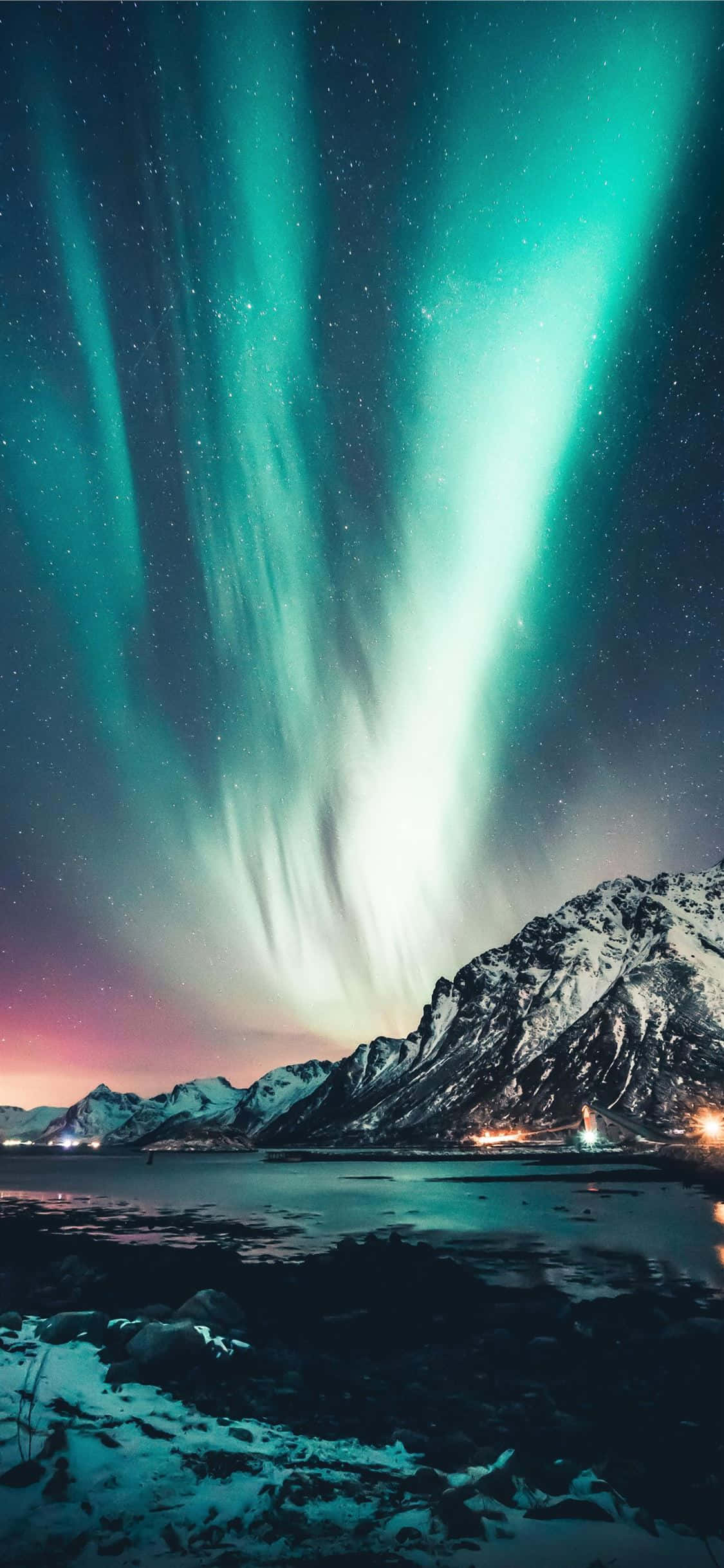 Norway 桌布 壁紙 — 充滿活力的綠色北極光在繁星點點的夜空中舞動，映照著積雪的山脈和冰凍的湖泊。