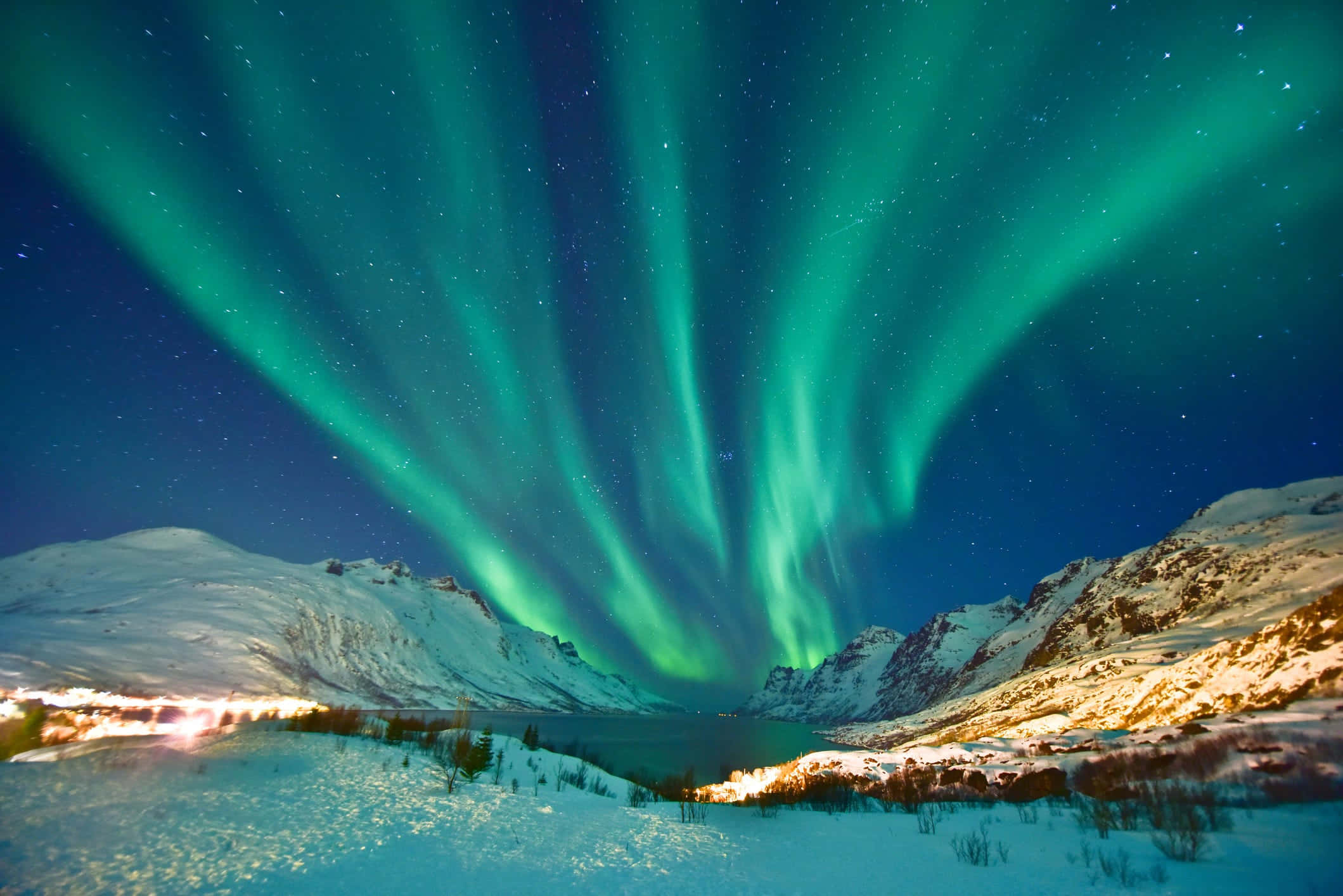 aurora borealis 桌布 壁紙 — 充滿活力的綠色北極光在雪覆蓋的山脈和冰凍湖泊上方的星空夜空中舞動。