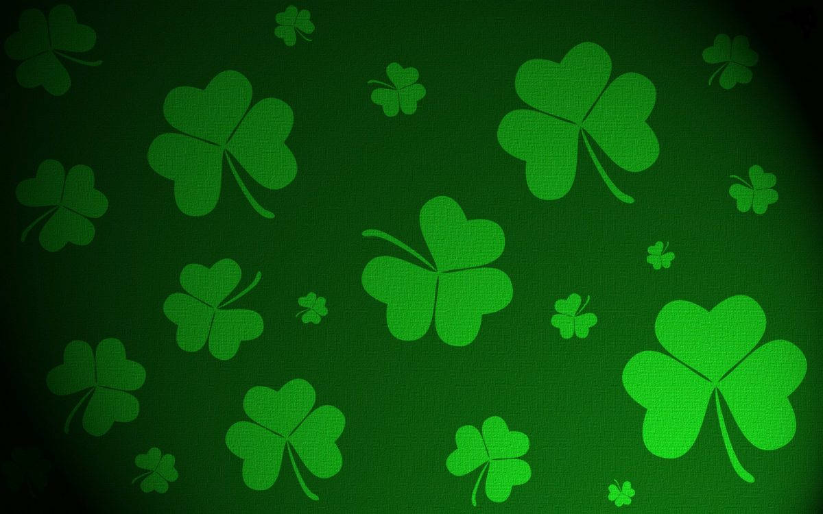 Happy St Patricks Day 桌布 壁紙 — 充滿活力的綠色四葉草漂浮在帶有漸變照明的紋理深綠色背景上。