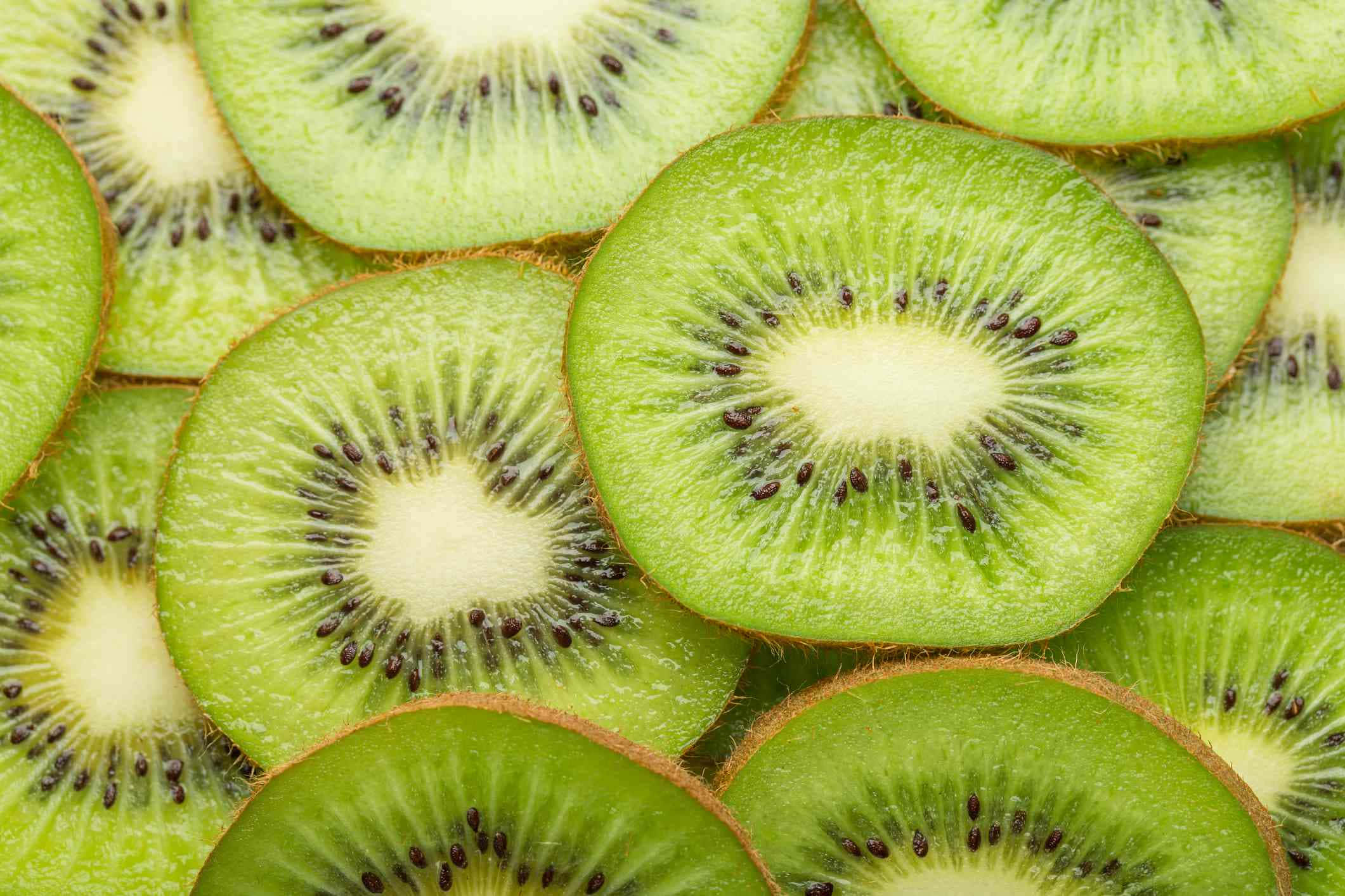 Winter Fruits 桌布 壁紙 — 充滿活力的綠色奇異果切片特寫，展現多汁果肉和黑色種子。