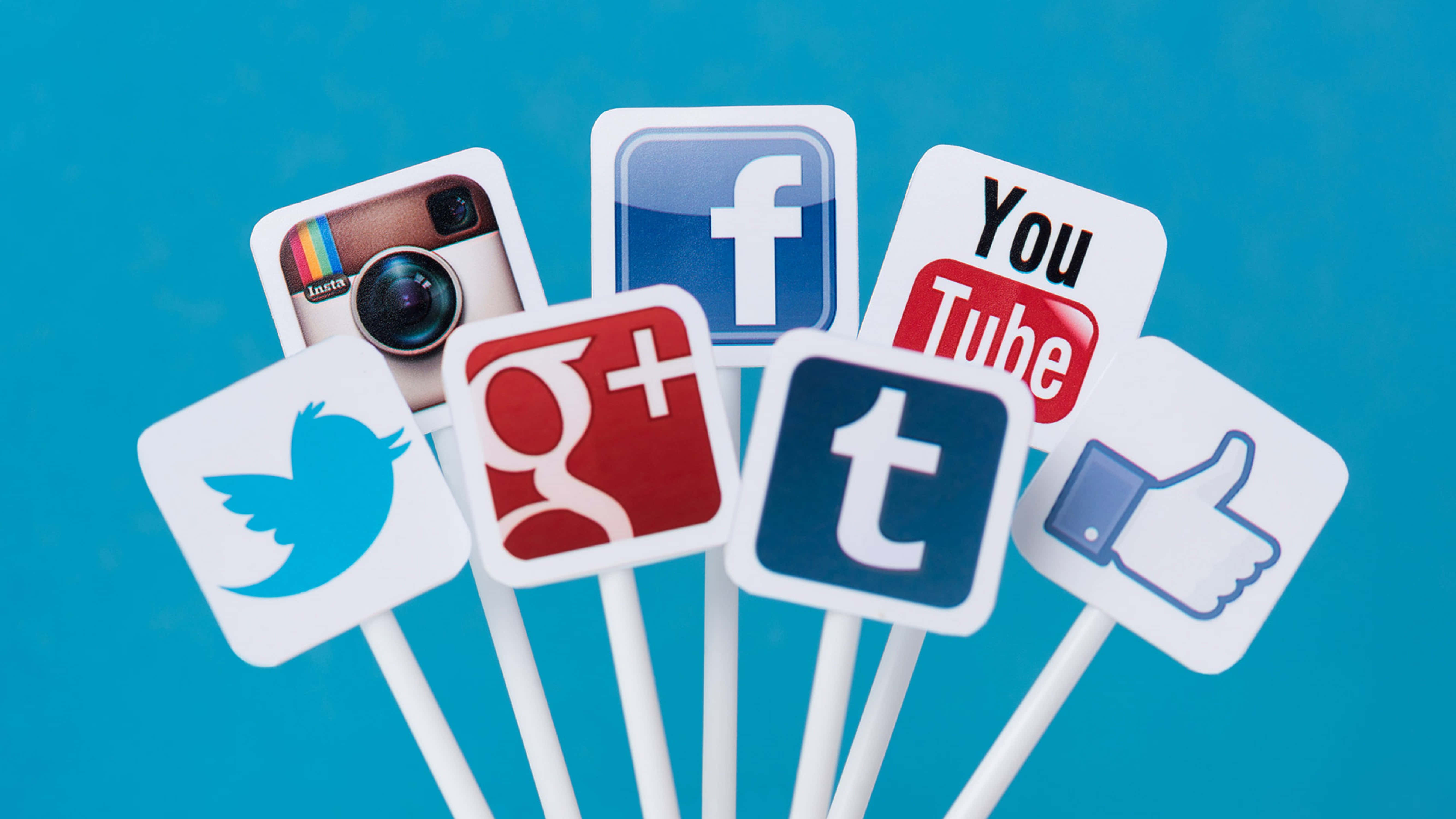 4K Social Media 桌布 壁紙 — 充滿活力的藍色背景上，白色棒狀物上帶有標誌性的社交媒體標誌，排列成扇形。