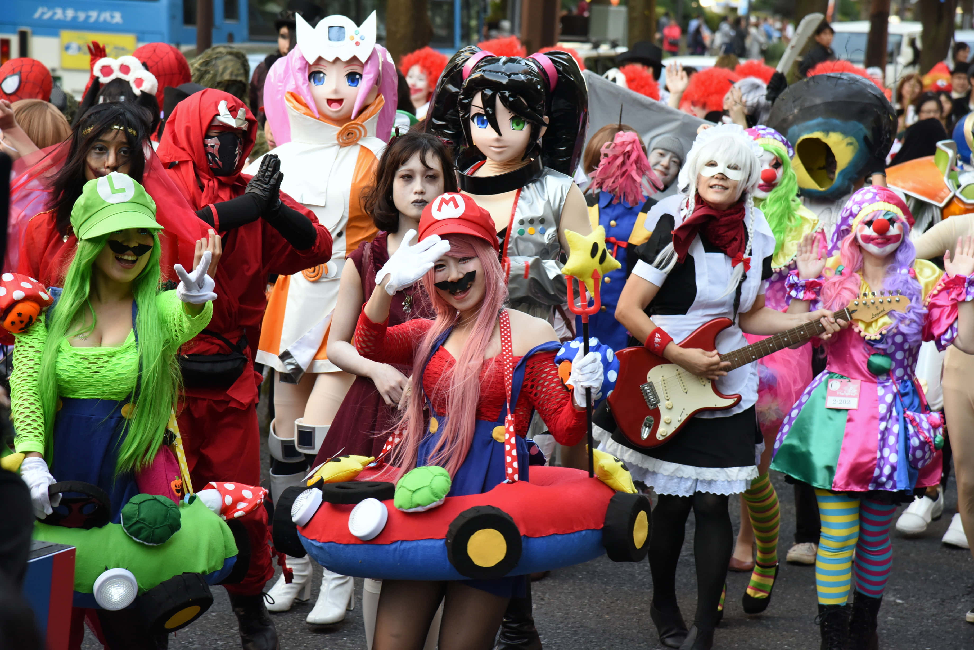 Halloween Parades 桌布 壁紙 — 充滿活力的街頭遊行，cosplayers穿著色彩繽紛的動漫服裝擺姿勢拍照。