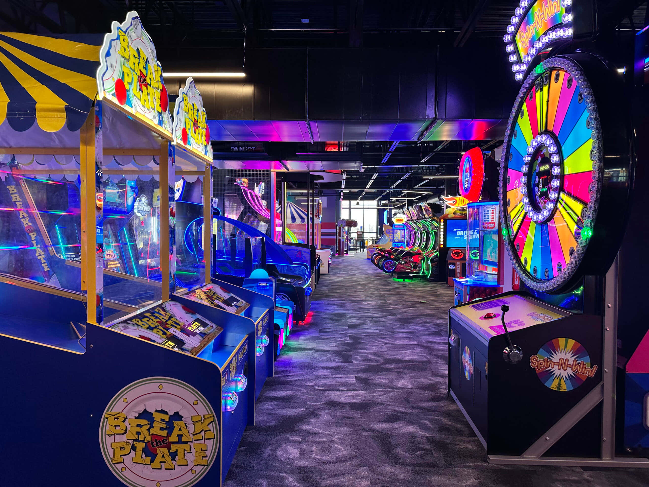 Arcade Games 桌布 壁紙 — 充滿活力的遊戲機走廊，在黑暗天花下閃爍著霓虹燈光和色彩繽紛的遊戲機。
