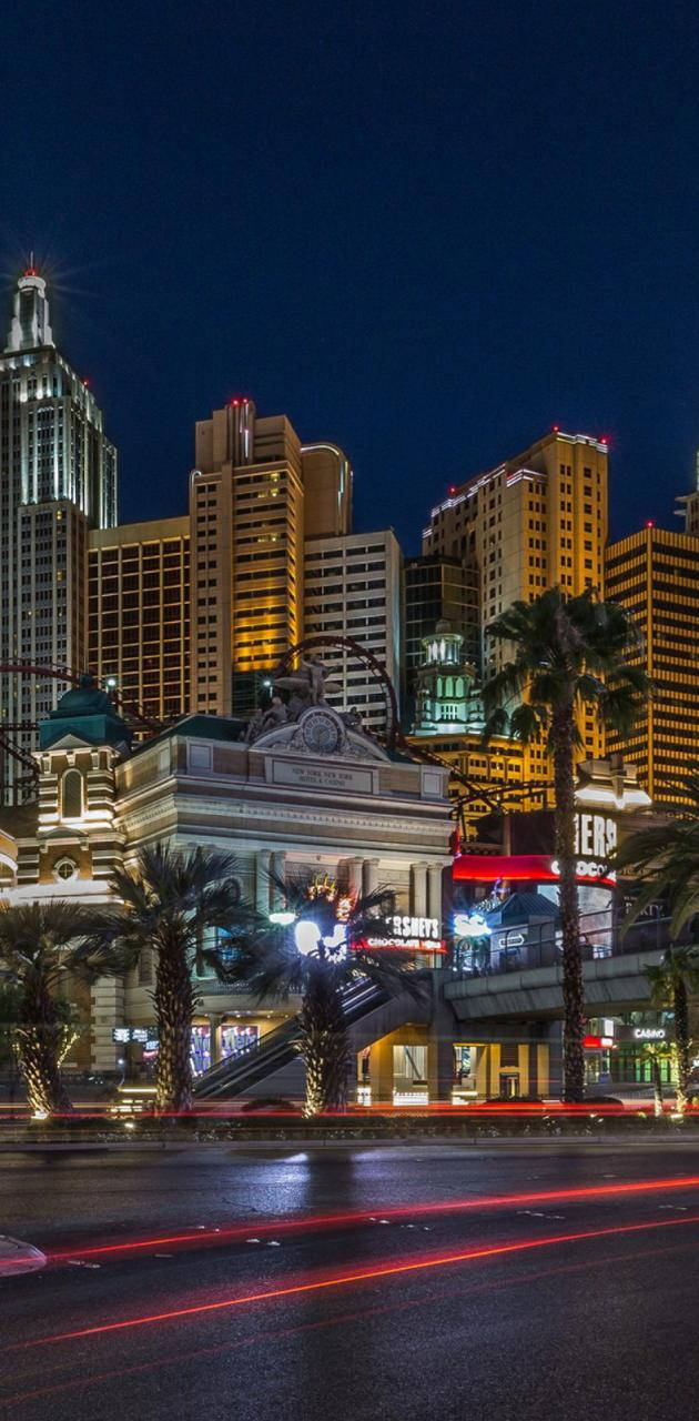 Las Vegas Night 桌布 壁紙 — 充滿活力的霓虹燈照亮了繁華的拉斯維加斯夜景，棕櫚樹和濕漉漉的街道上劃過的車燈。