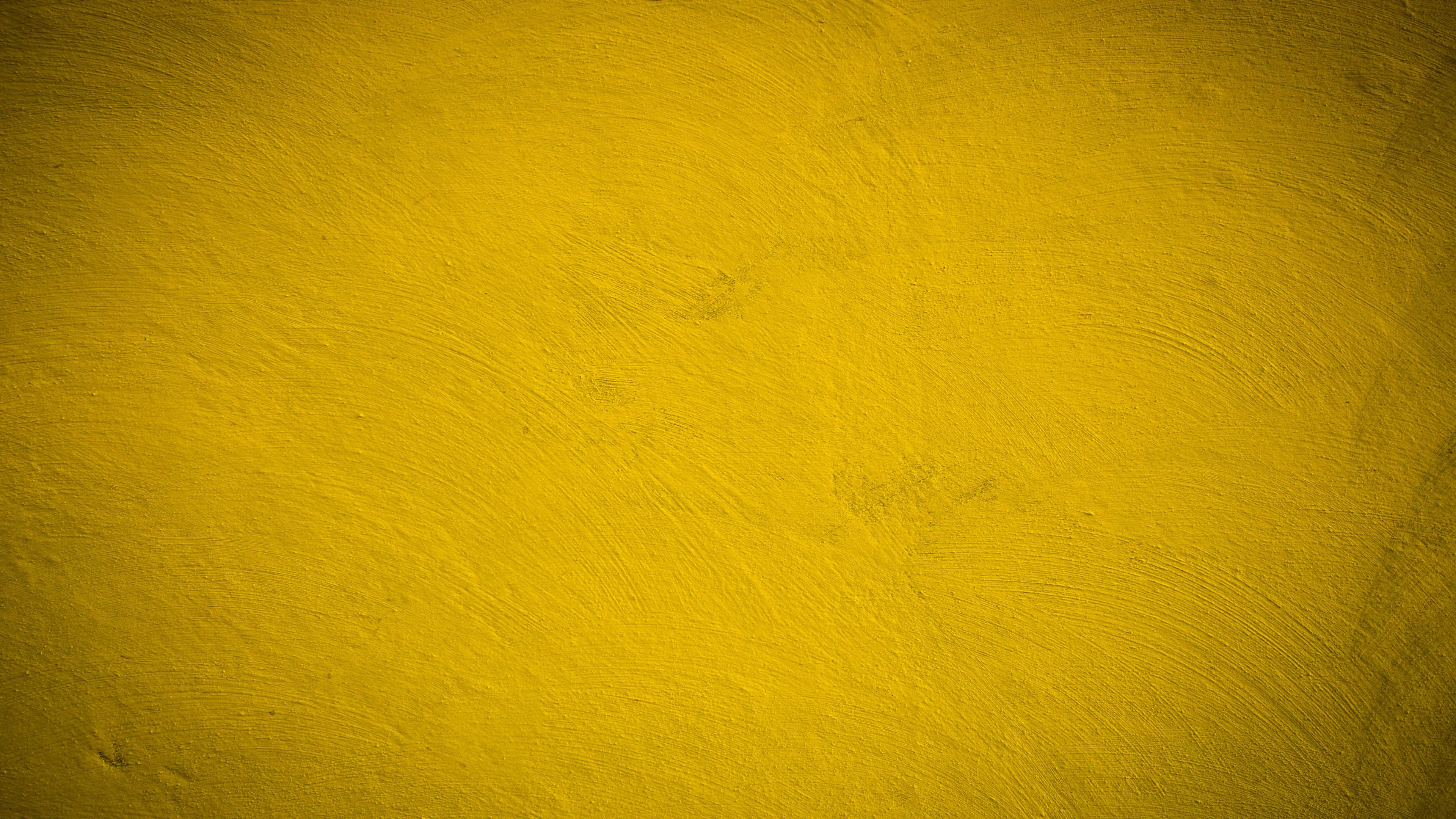 Yellow Grunge 桌布 壁紙 — 充滿活力的黃色紋理牆壁，帶有細微的筆觸和不均勻的表面細節。