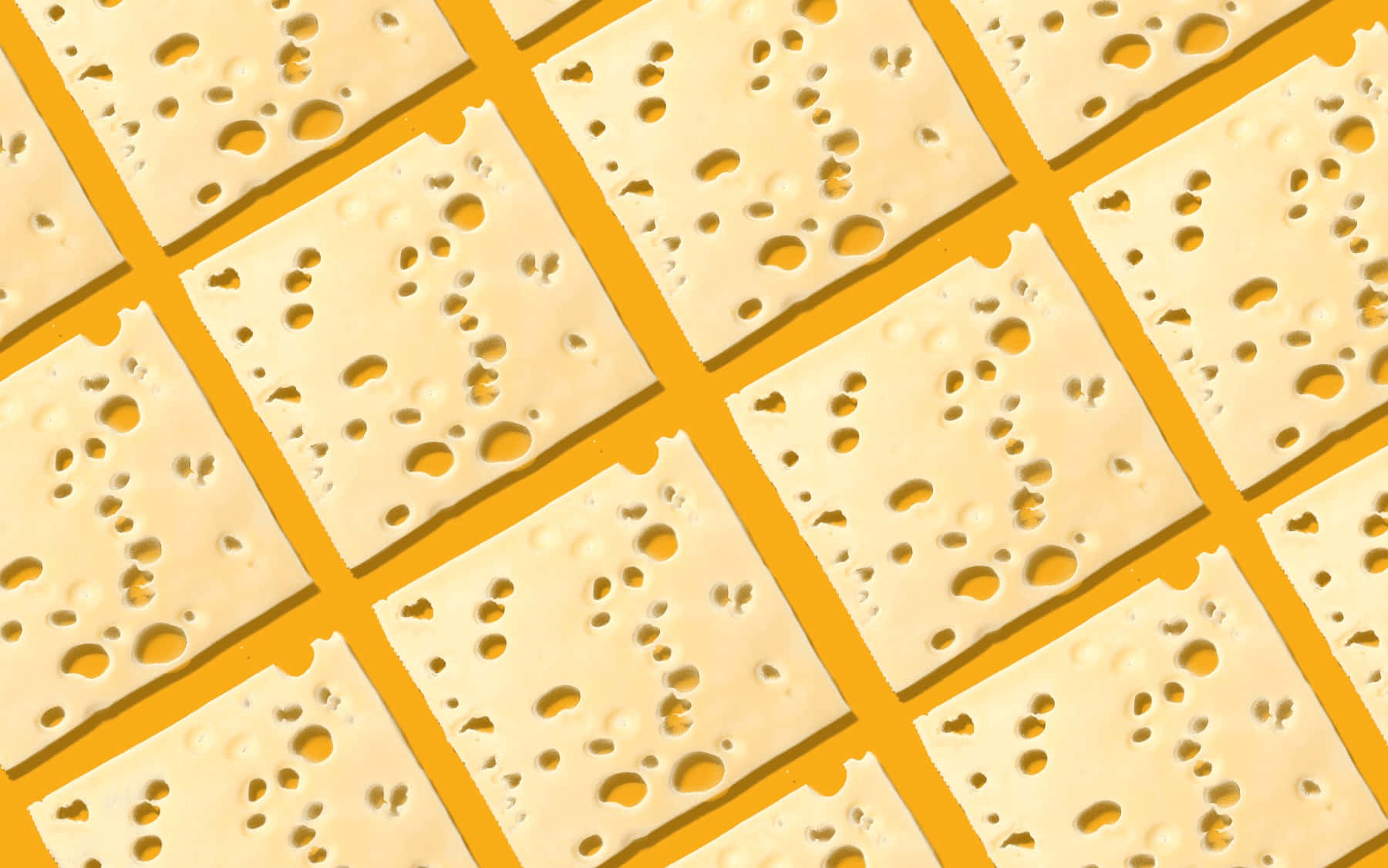 Cheese 桌布 壁紙 — 充滿活力的黃色背景，整齊排列著帶有特徵孔洞的瑞士芝士方形切片。